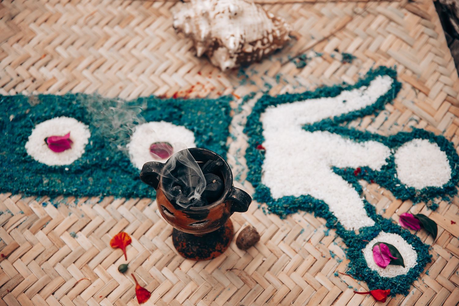 Coffee grinder and decorative elements arranged on a woven mat with teal and white patterns.