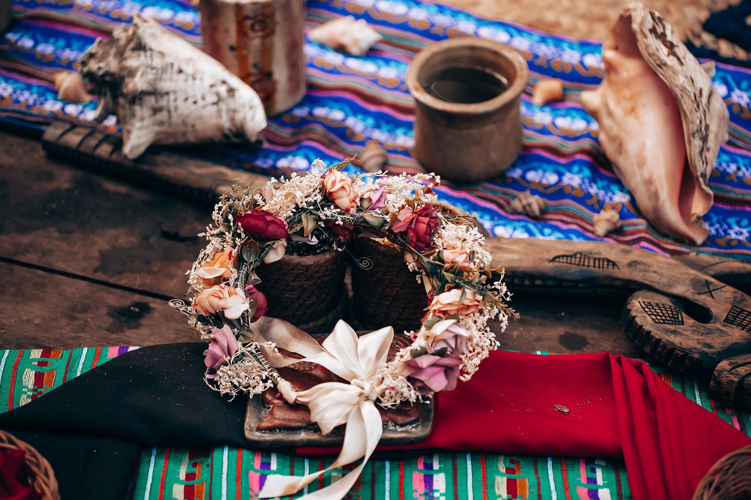 Delicate floral crown with pink and white dried flowers arranged on a rustic wooden surface.