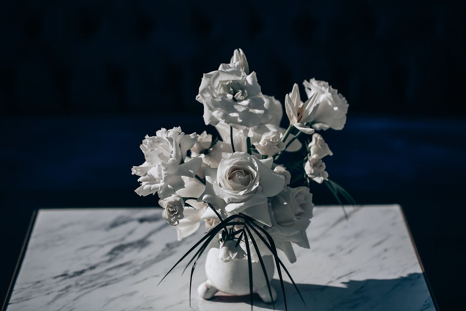 White floral arrangements on dark background create elegant contrast.