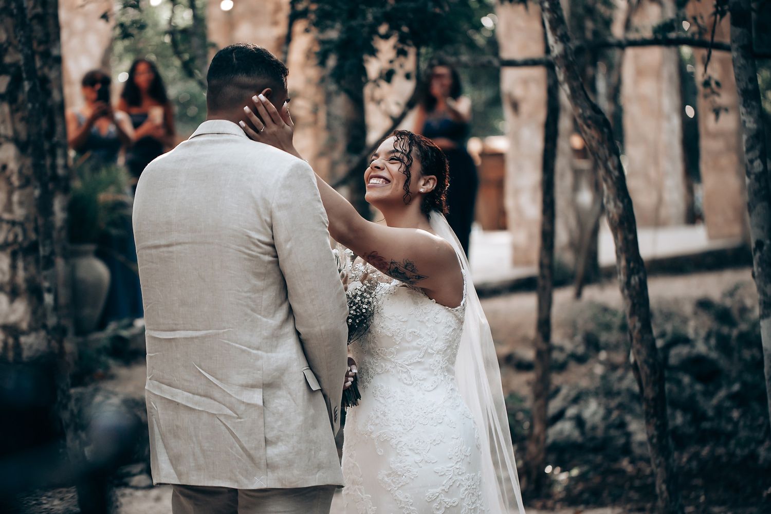 A couple shares a romantic moment in an outdoor forest setting during their wedding ceremony.