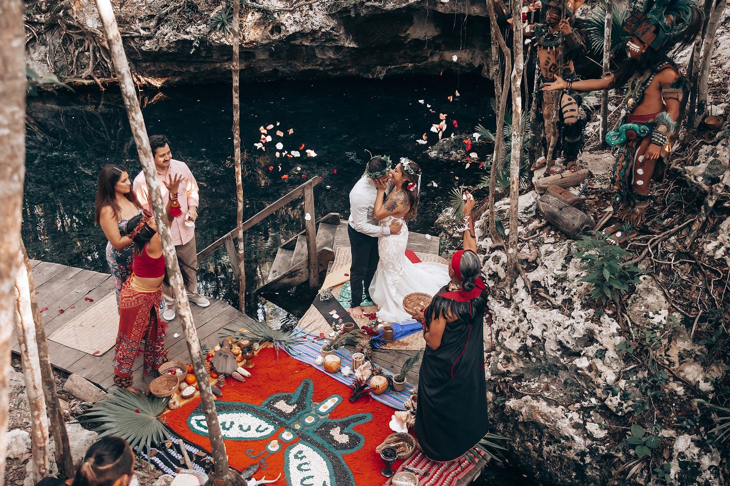 Wedding celebration in a forest setting with red picnic blankets and natural decor.