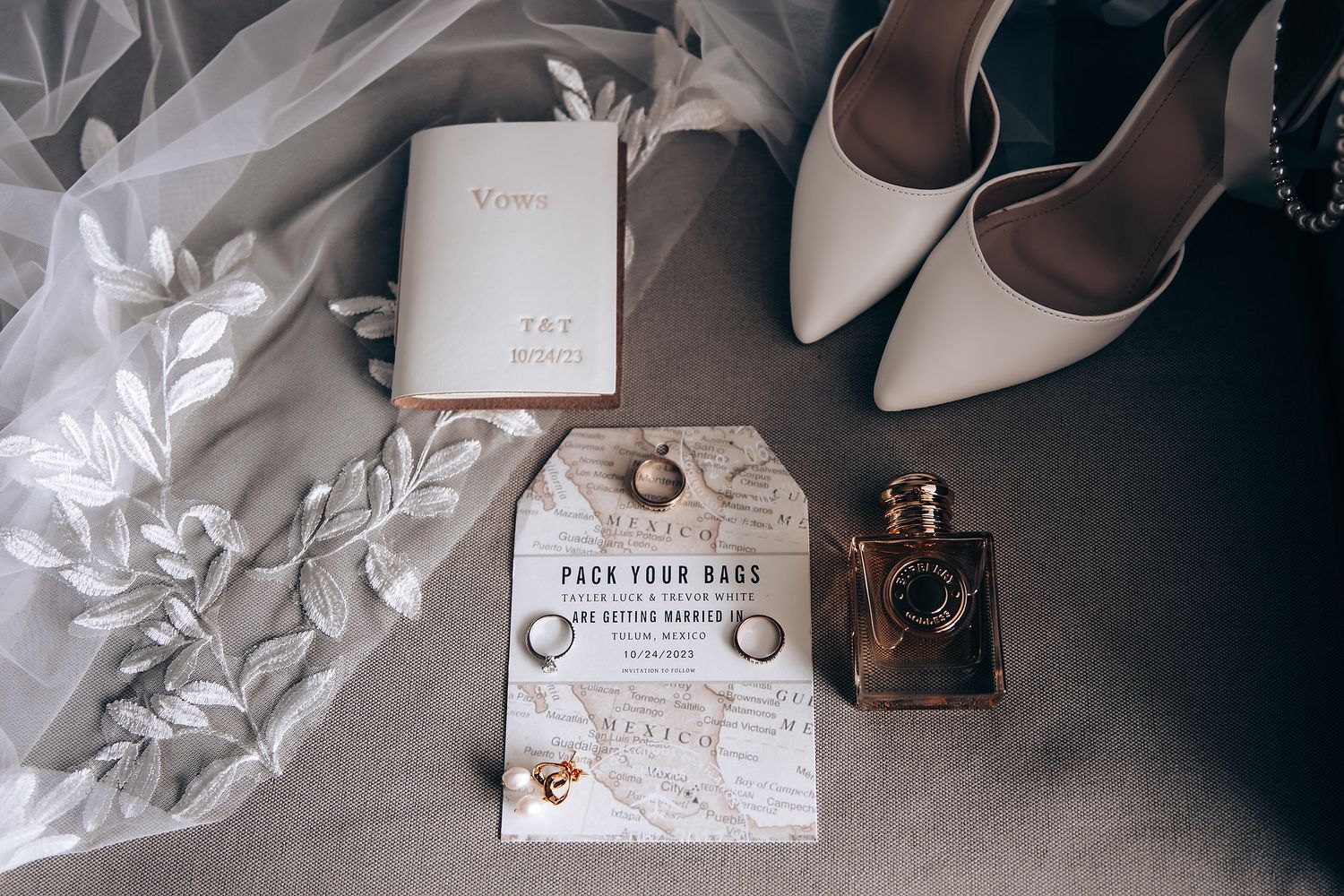 Wedding details flatlay with invitation, rings, shoes, and delicate decor elements in neutral tones.