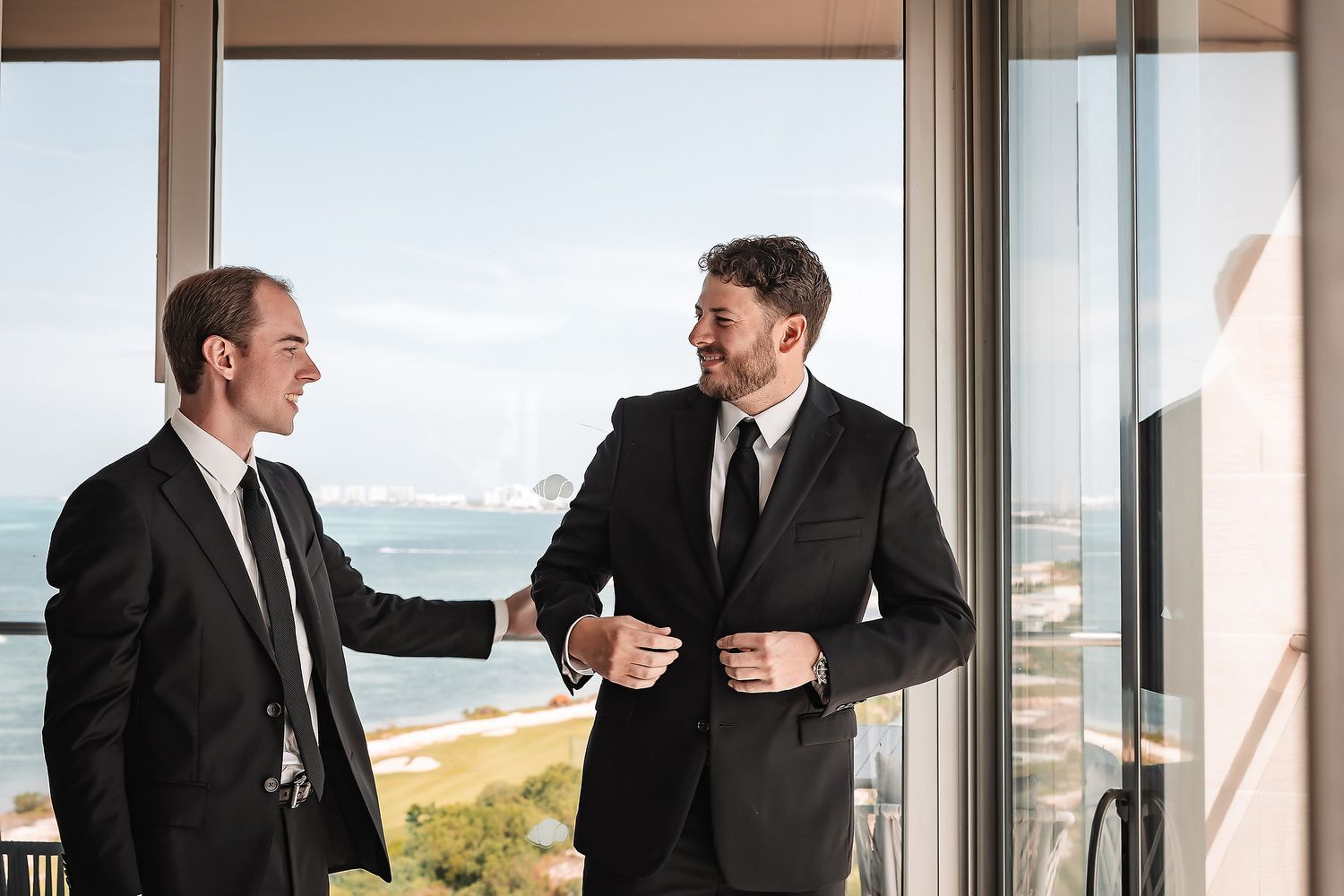 Group of men in black suits laughing and having fun together during a formal event.