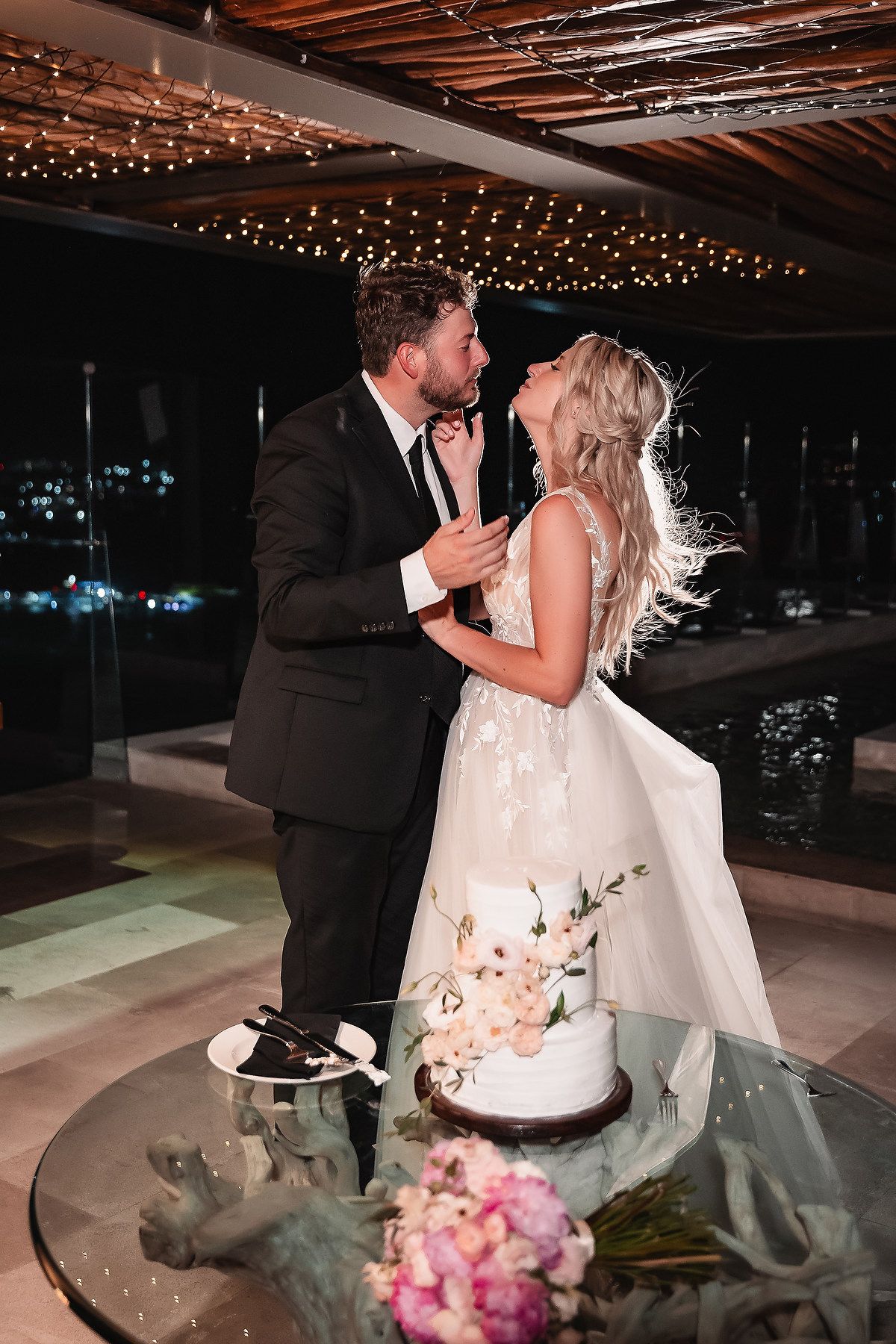 Wedding reception scene with string lights and cake cutting moment.