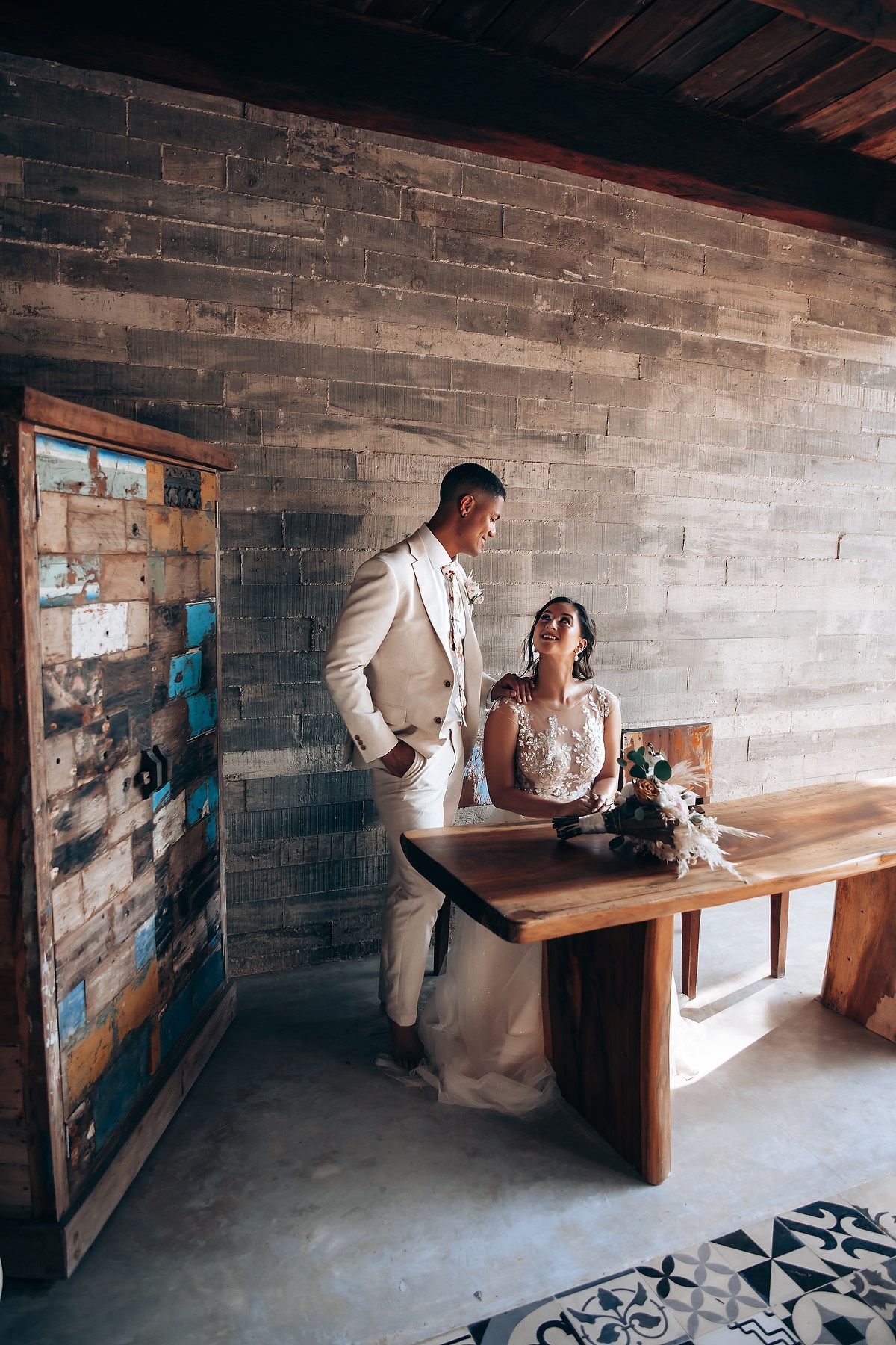 A rustic brick-walled room with wooden benches serves as a charming wedding venue setting.