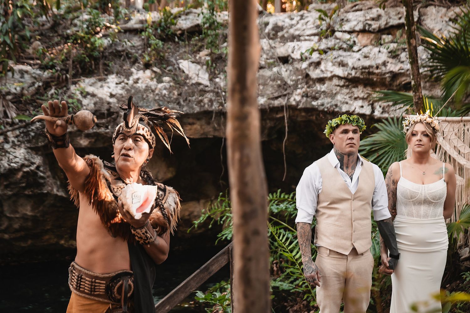 Mayan shaman performs traditional wedding ceremony for couple in lush jungle cenote setting in Mexico.