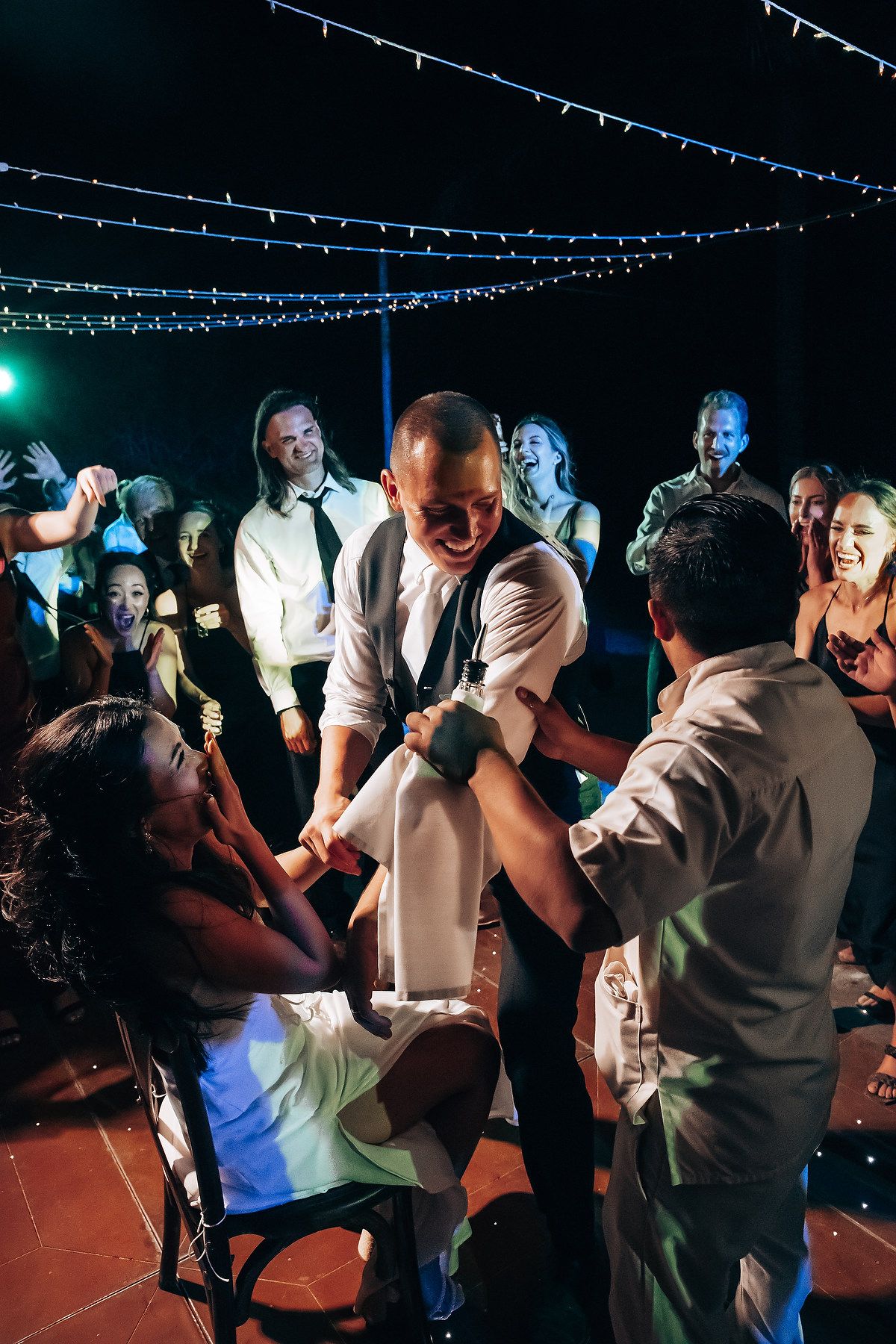 Wedding reception dance floor with string lights overhead and guests dancing in a festive atmosphere.