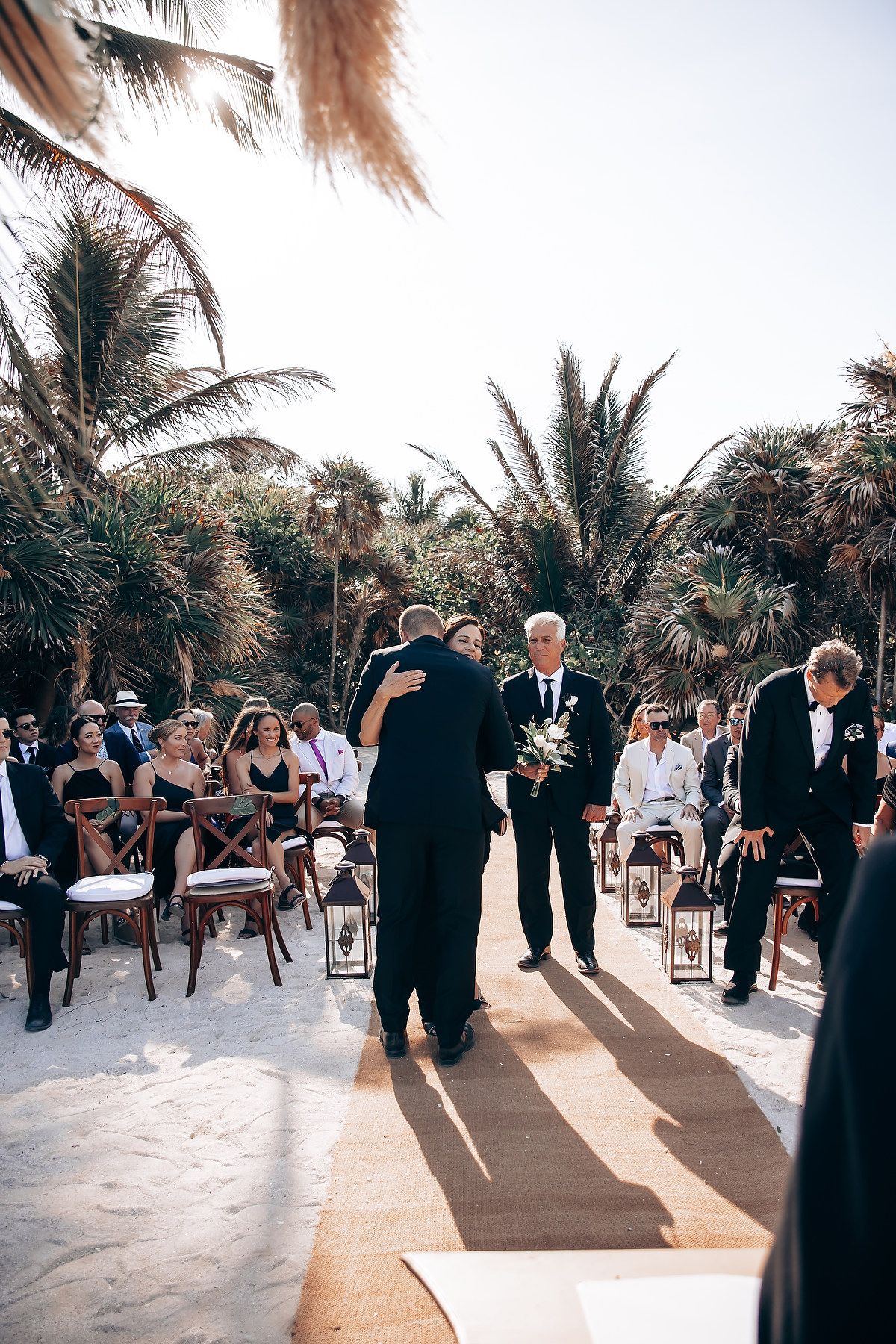Outdoor wedding ceremony setup with wooden chairs and tropical palm trees creating a natural aisle.