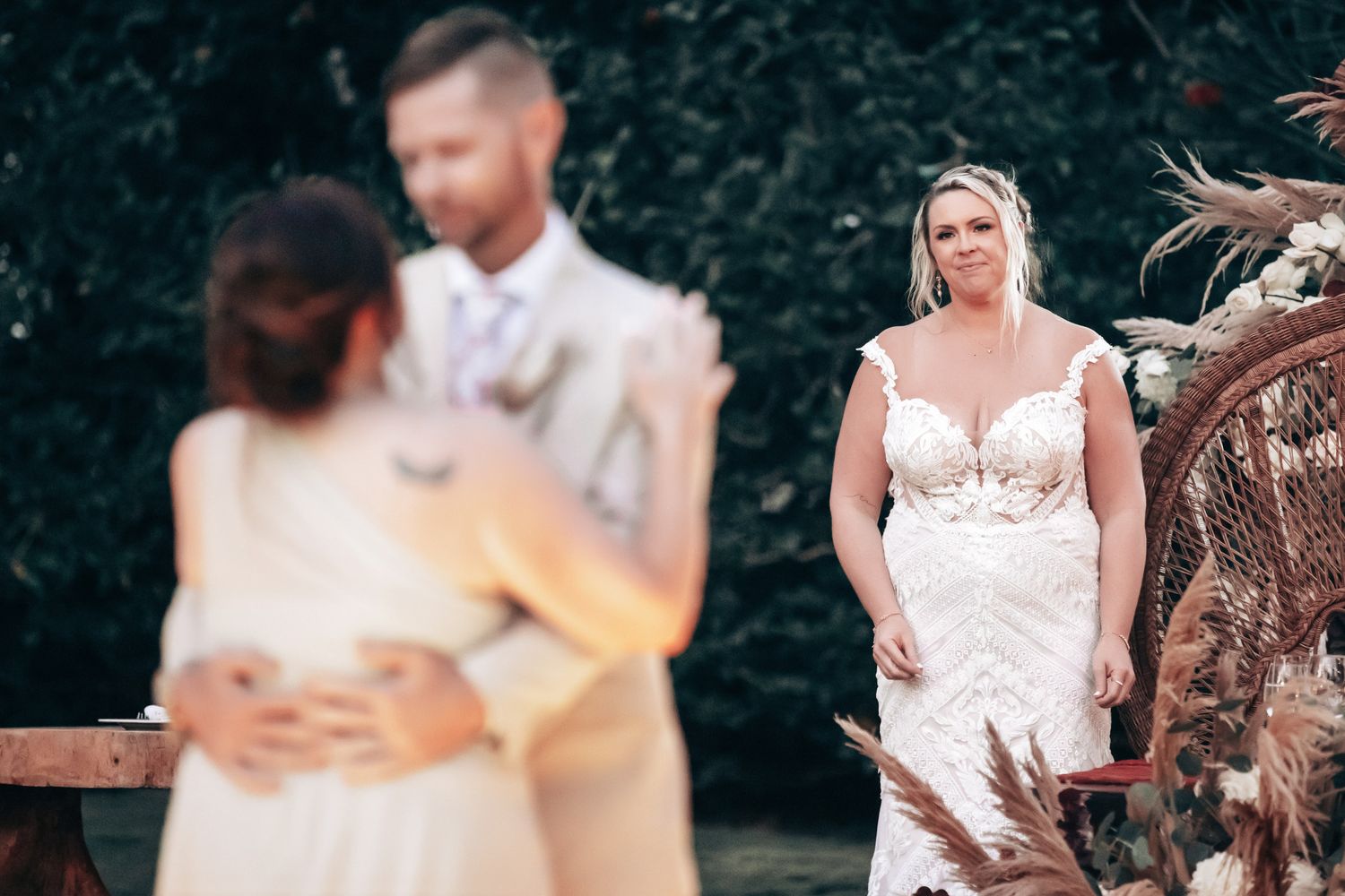 A tearful bride watches emotionally as the officiant performs the wedding ceremony at a boho outdoor wedding.