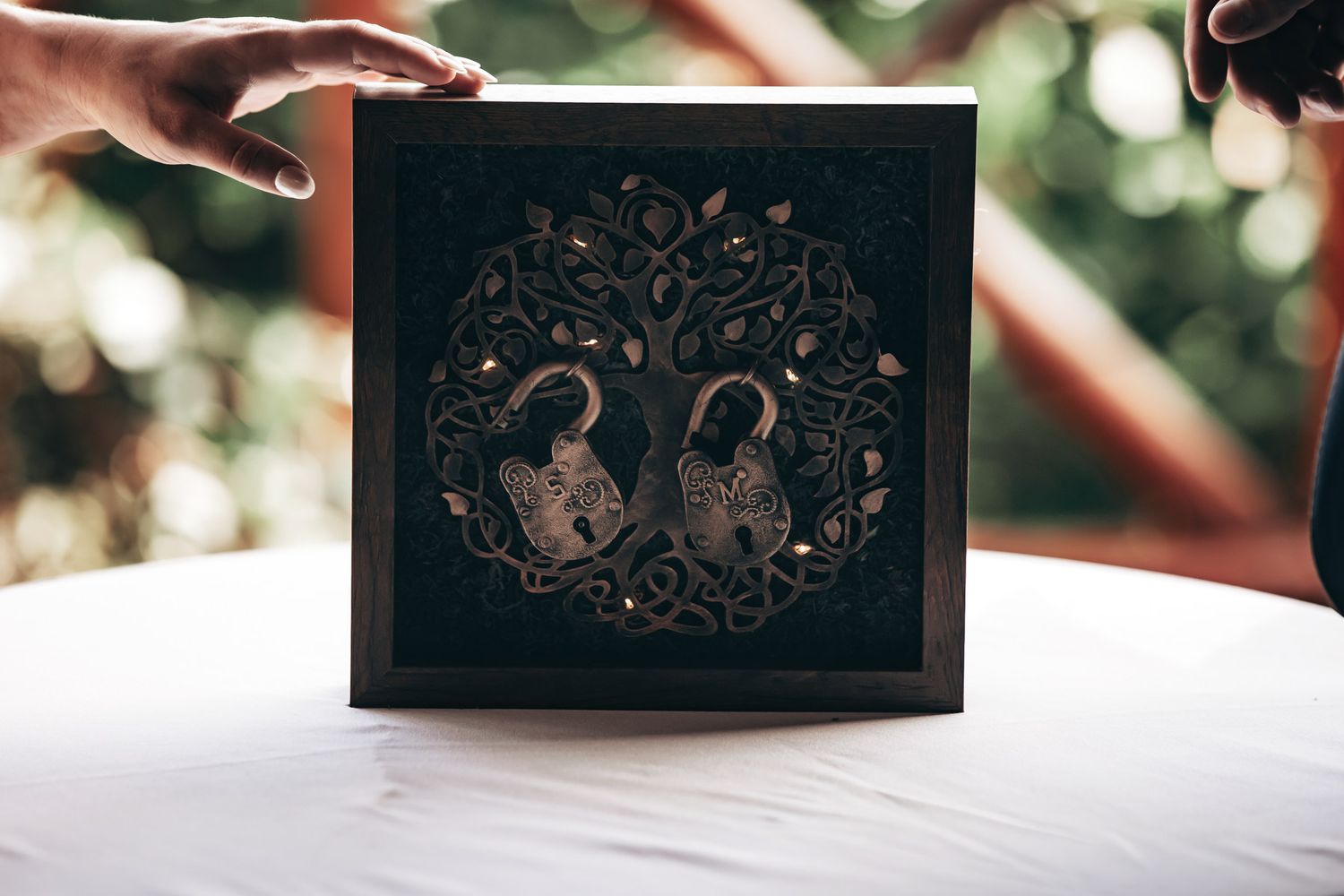 Decorative wooden shadow box featuring an intricate tree of life design with two ornate heart-shaped padlocks.