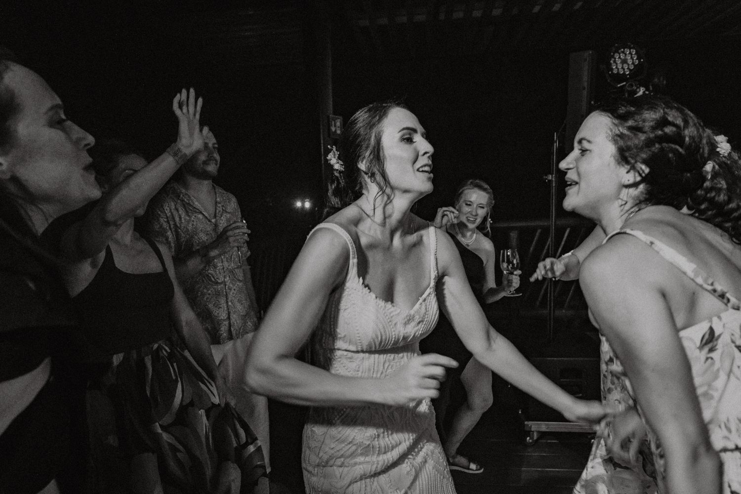 Black and white photo of women dancing and laughing together at a wedding reception celebration.
