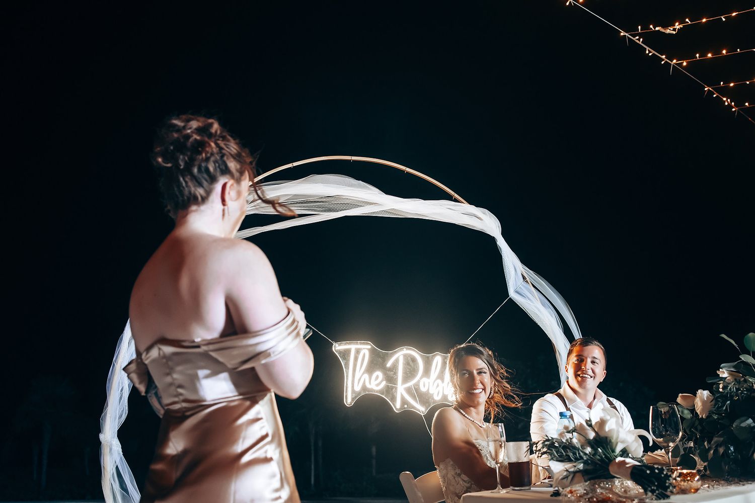 Romantic nighttime wedding reception with string lights and dancing silhouettes creating a dreamy atmosphere.