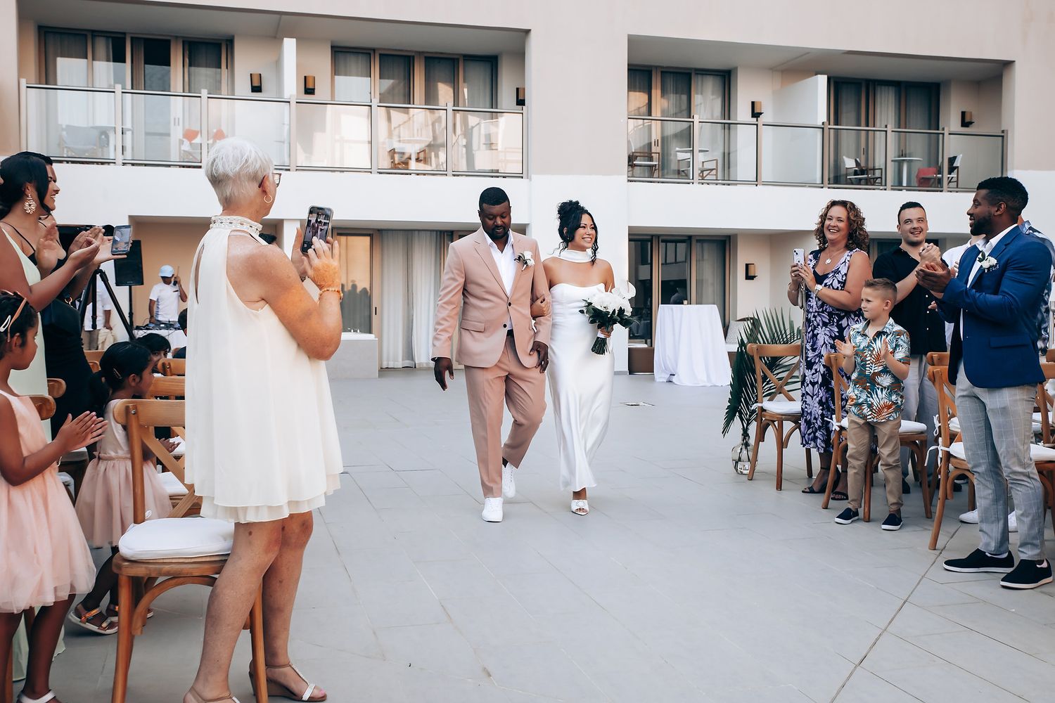 Modern building exterior with wedding party members gathered in formal attire.