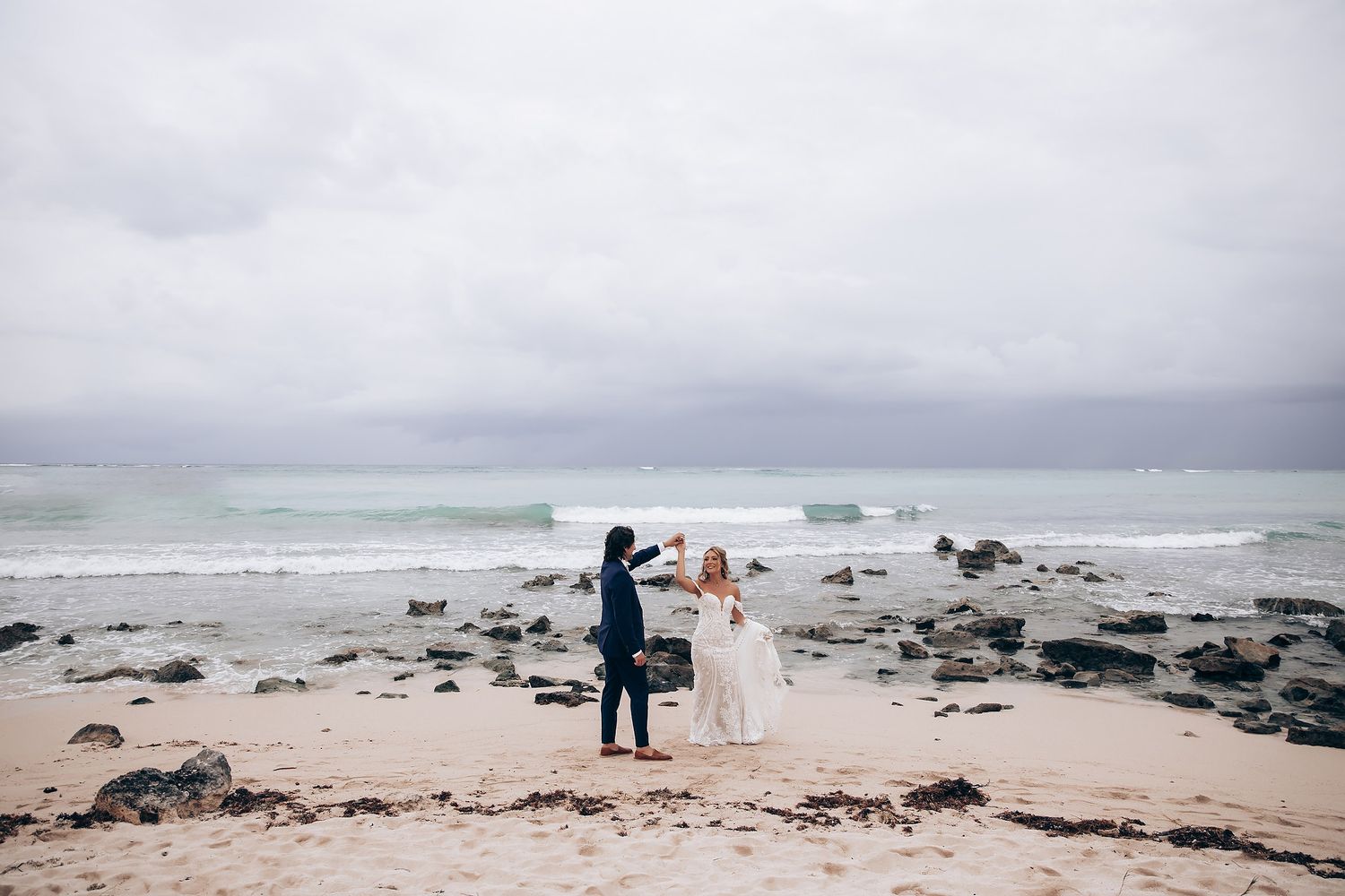Distant view of a couple walking along a rocky beach coastline.