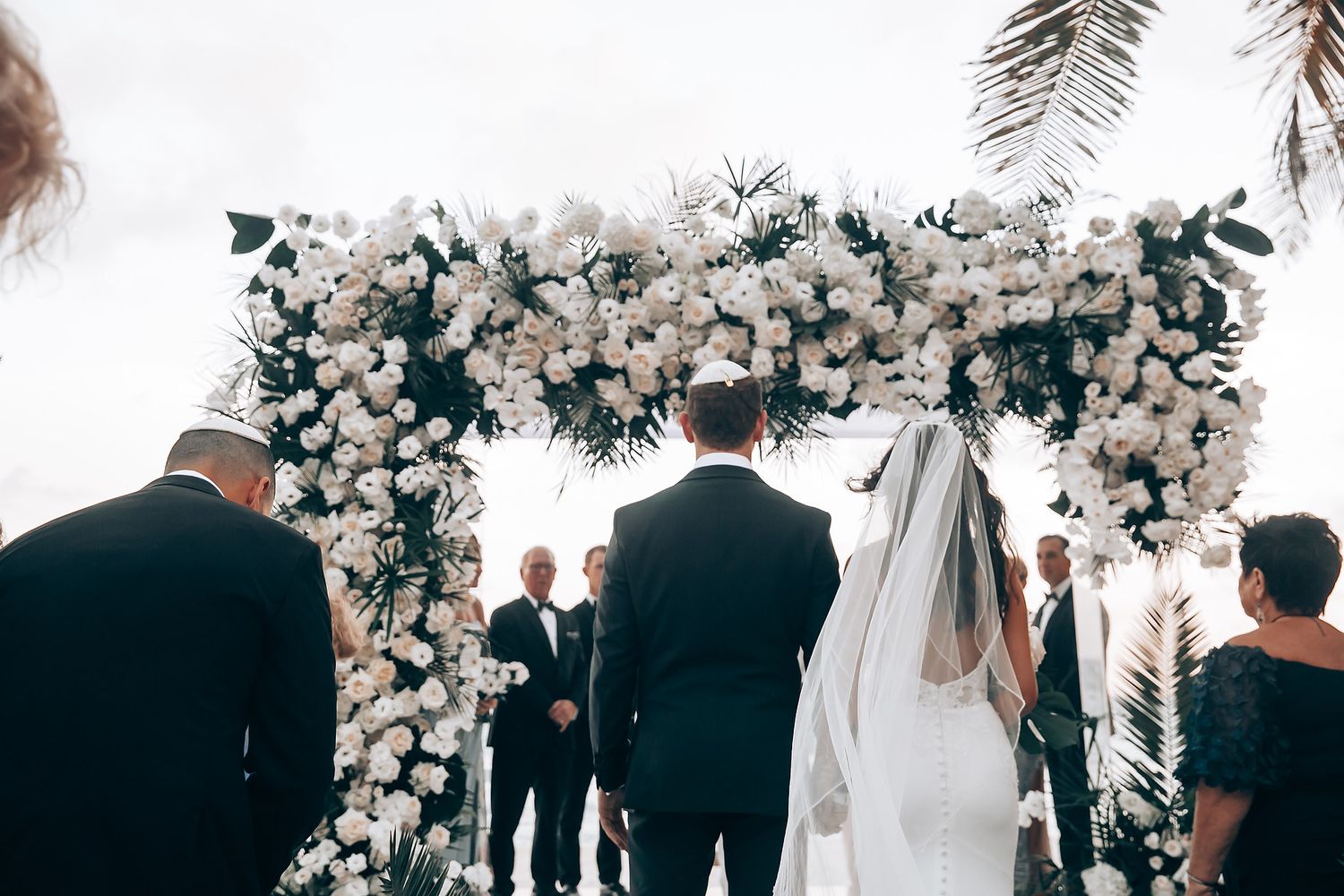Wedding ceremony aisle decorated with white floral arrangements and greenery.