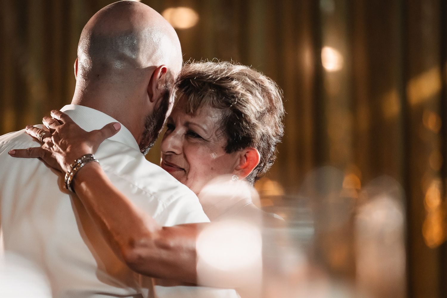 A couple dancing in an elegant indoor venue with warm lighting and wooden pillars creating an intimate atmosphere.
