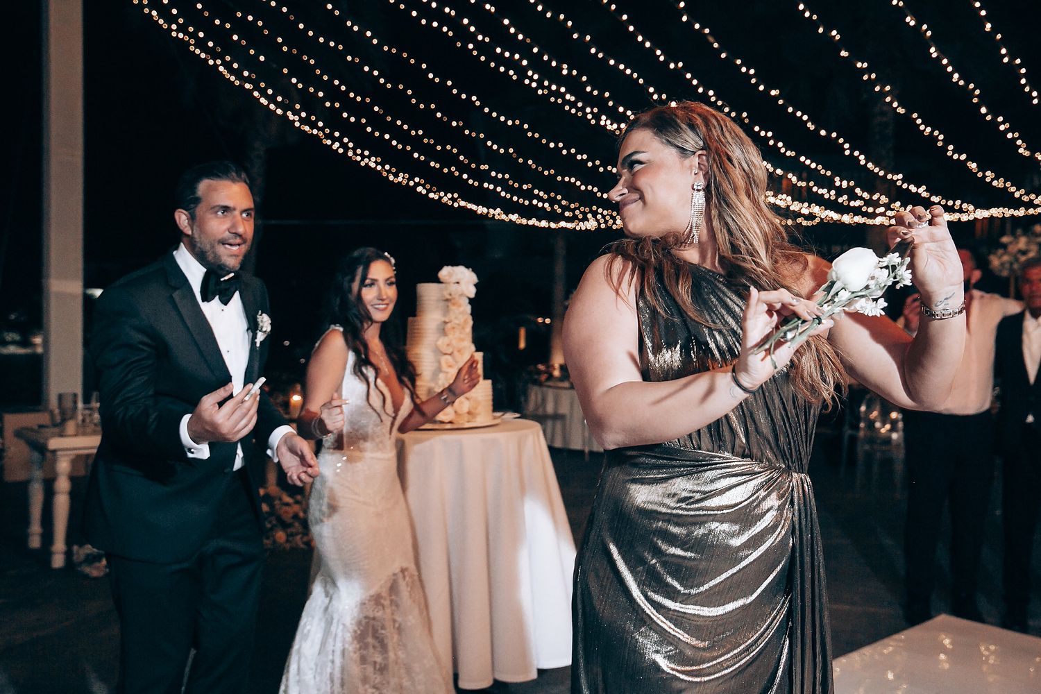 Wedding reception dance floor under sparkling string lights and chandeliers.