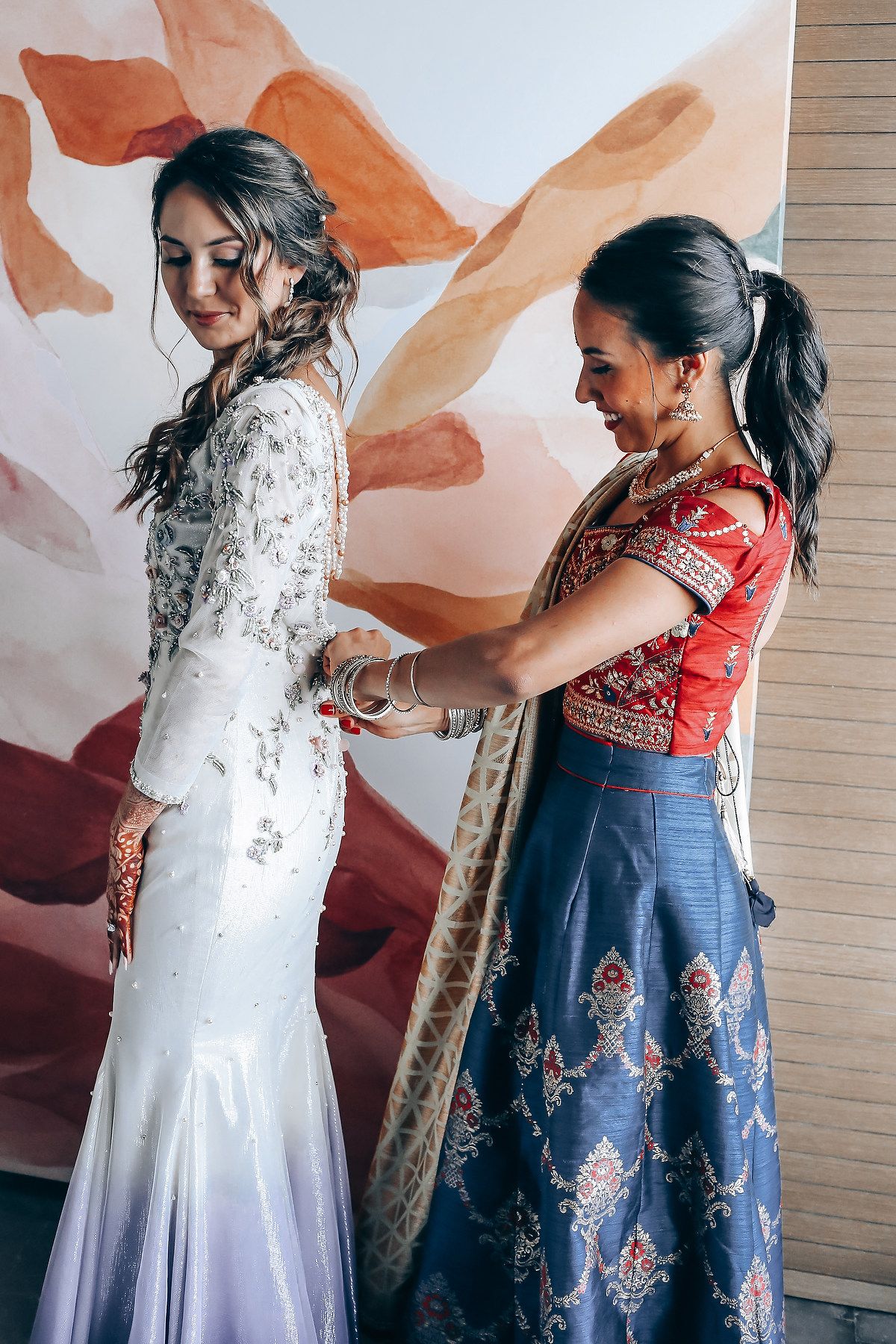 Sequence of photos showing someone getting dressed in a white wedding gown with help from an attendant.