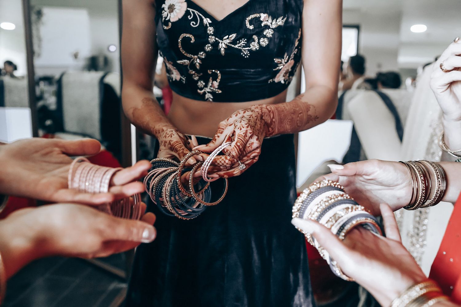Hands adorned with traditional bangles and jewelry during a cultural celebration.