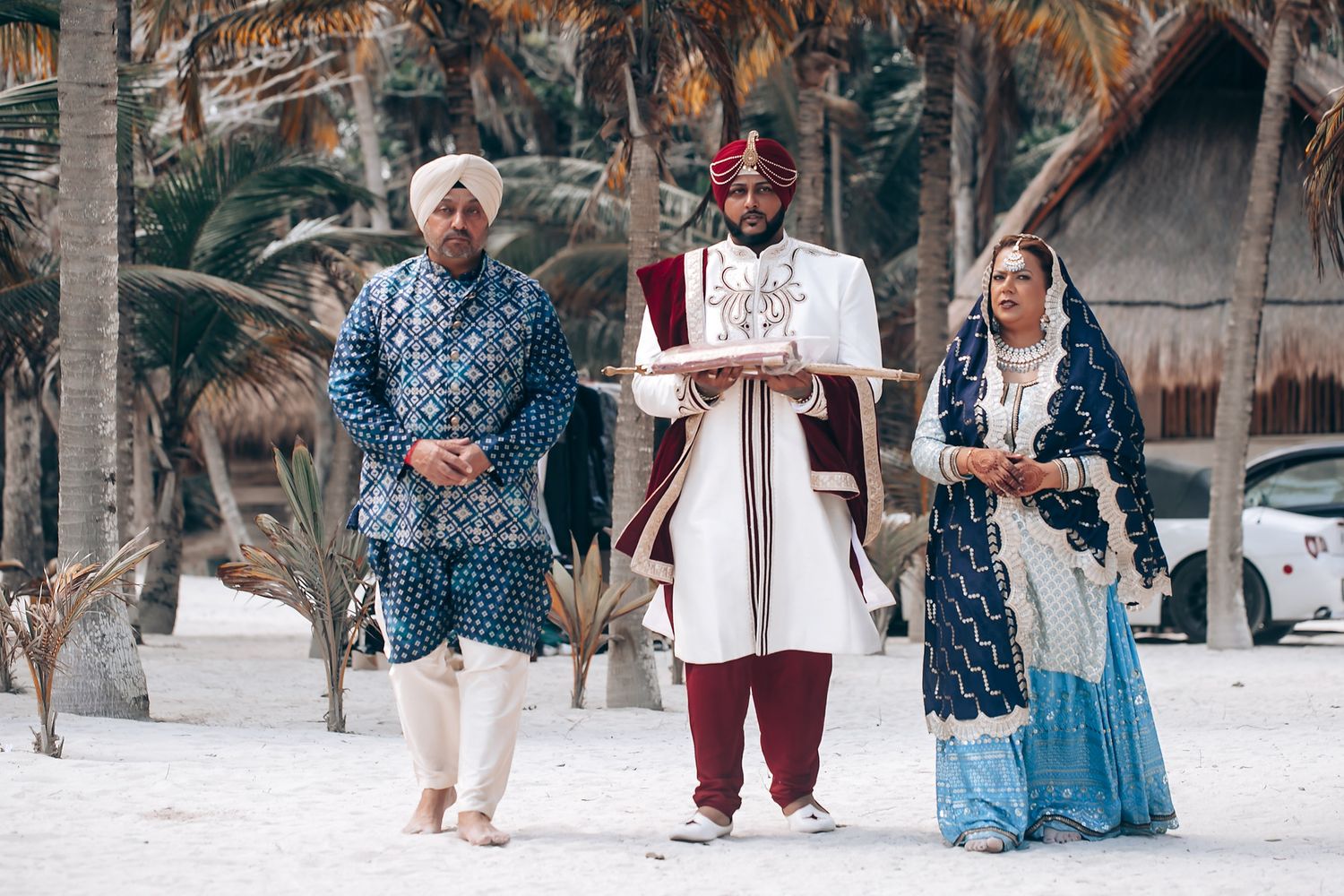 Wedding guests in traditional attire gathering at tropical beach venue.