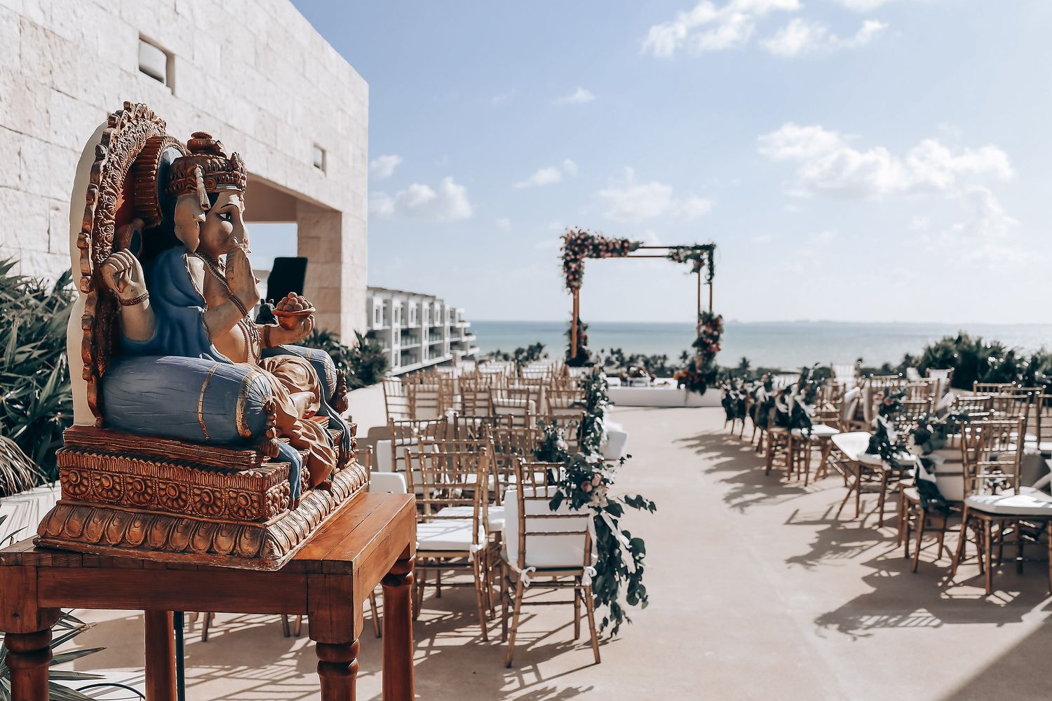 Beachfront wedding ceremony setup with white chairs and ocean view.