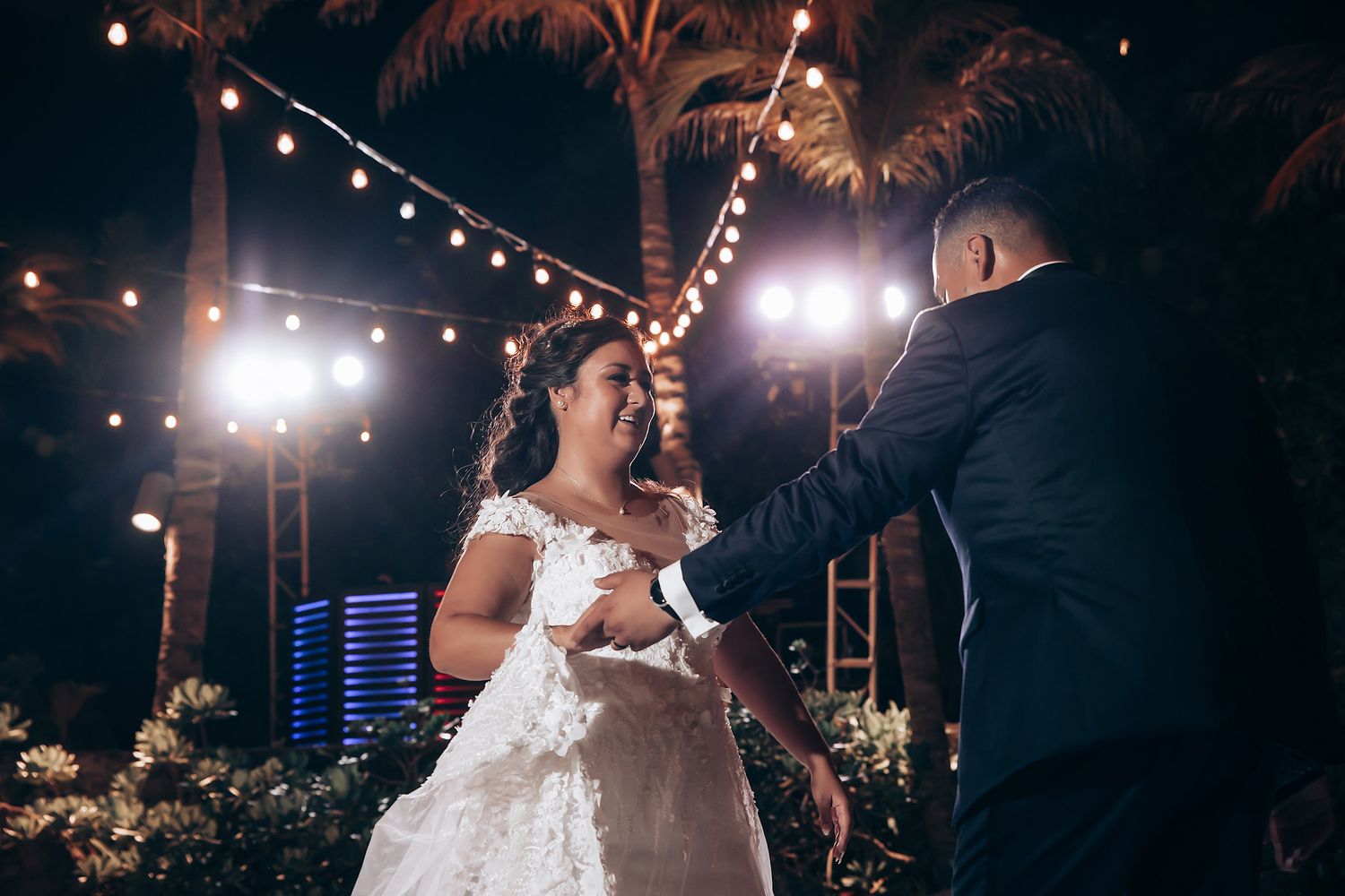 Evening celebration under string lights and palm trees at outdoor venue.