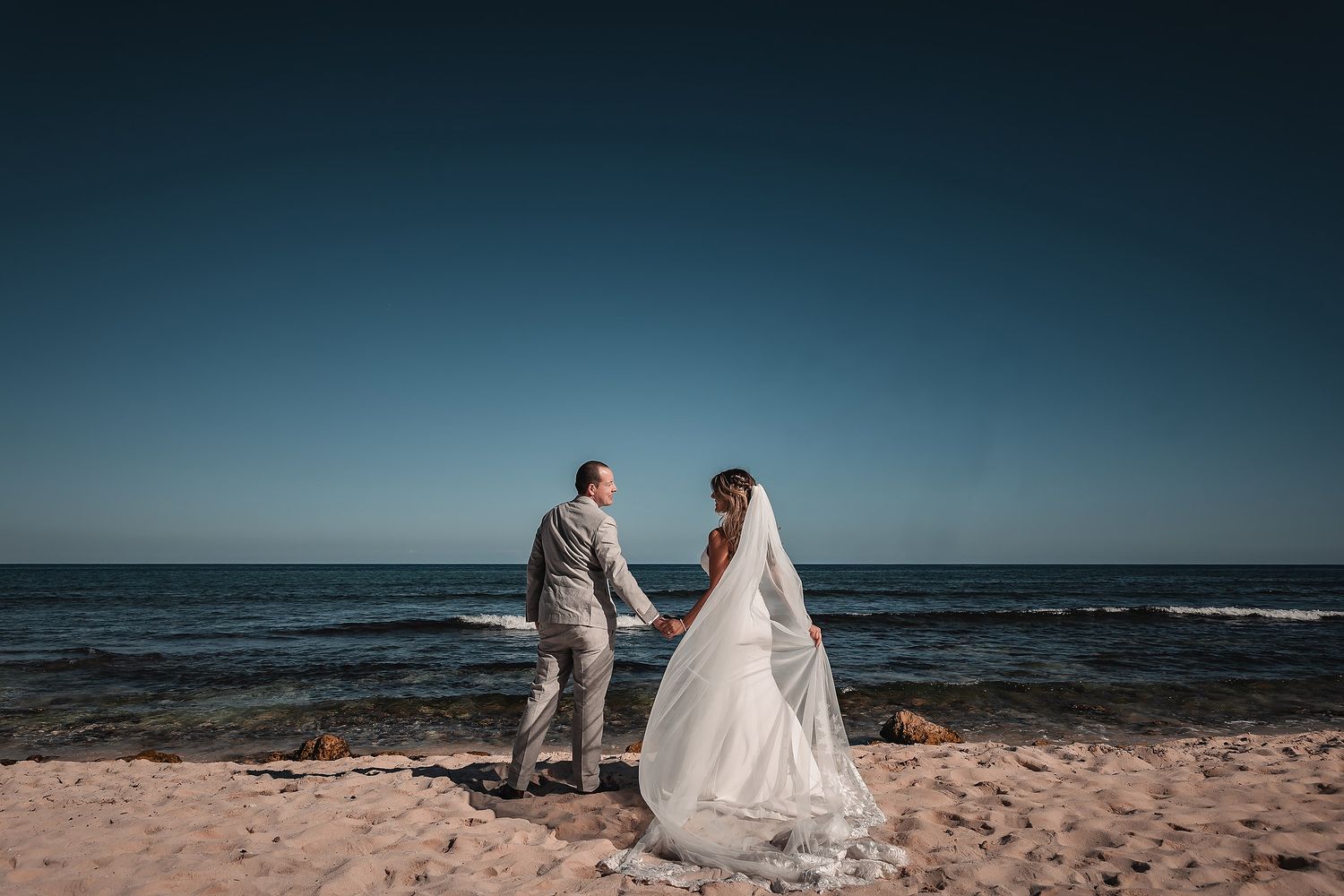 Bride and groom walking on the beach at Bahia Principe Tulum