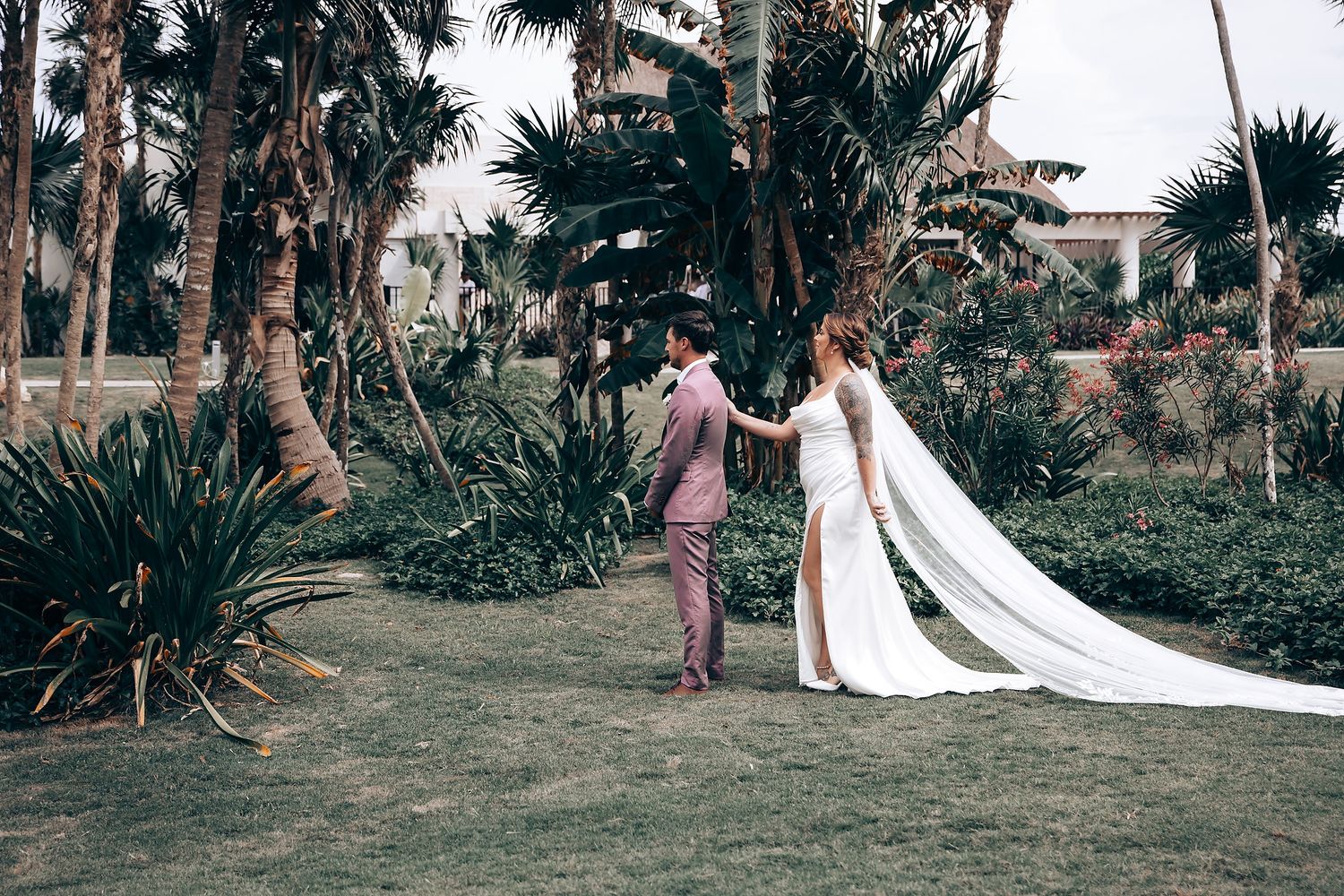 Wedding couple walking along a tropical palm-lined path at an outdoor venue.