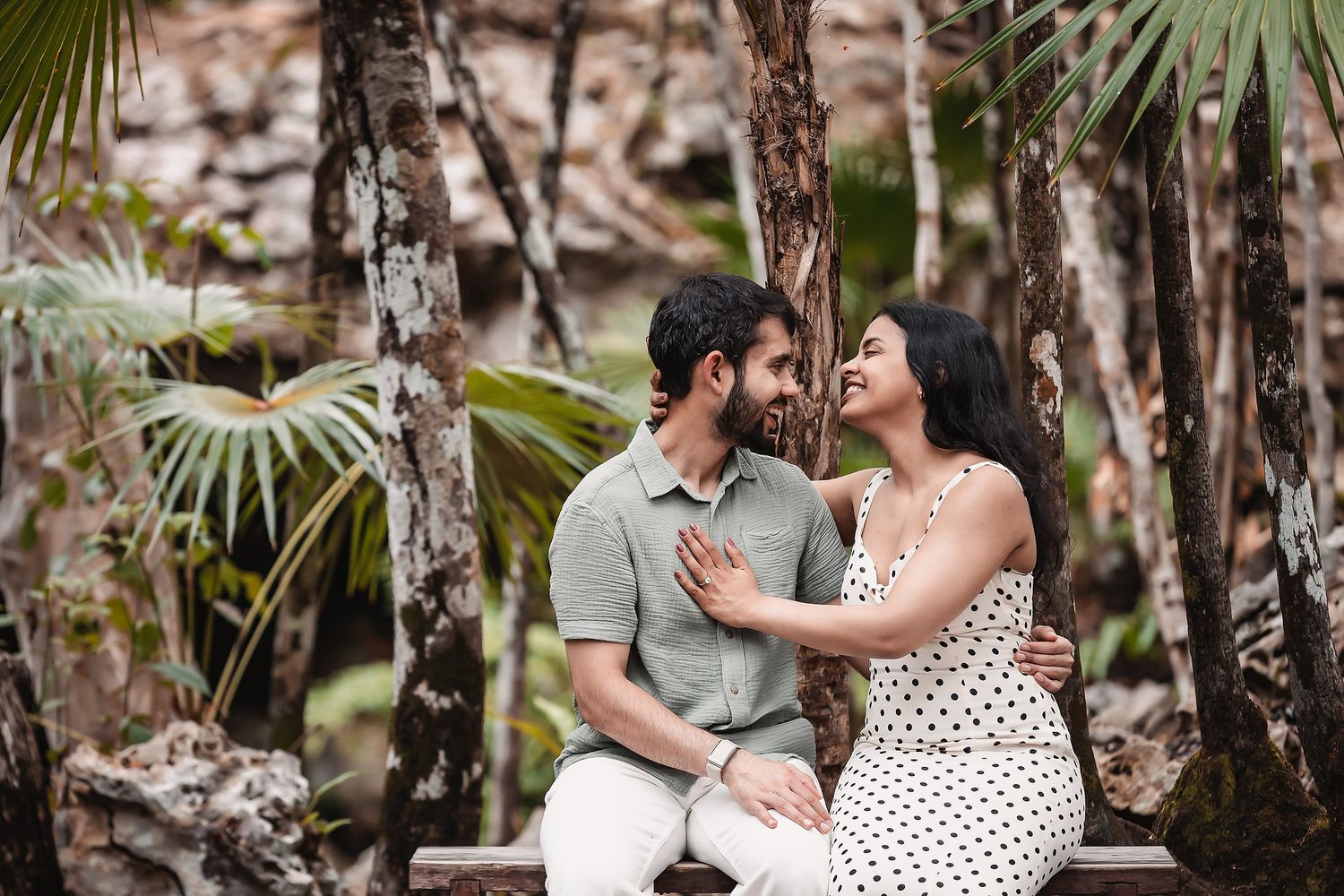 A couple shares romantic moments in a tropical setting with palm trees.