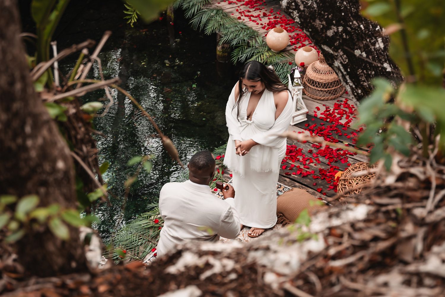 Emotional proposal moment captured in natural cave setting with red bohemian decor.
