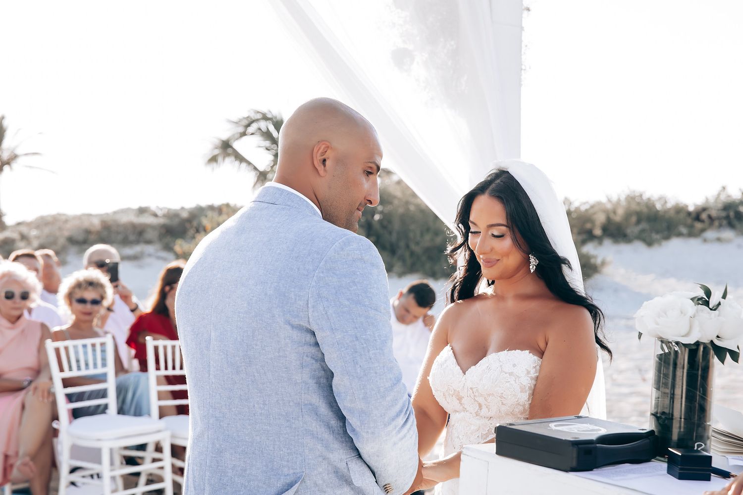 Intimate beach wedding ceremony moments with white decor and natural lighting.