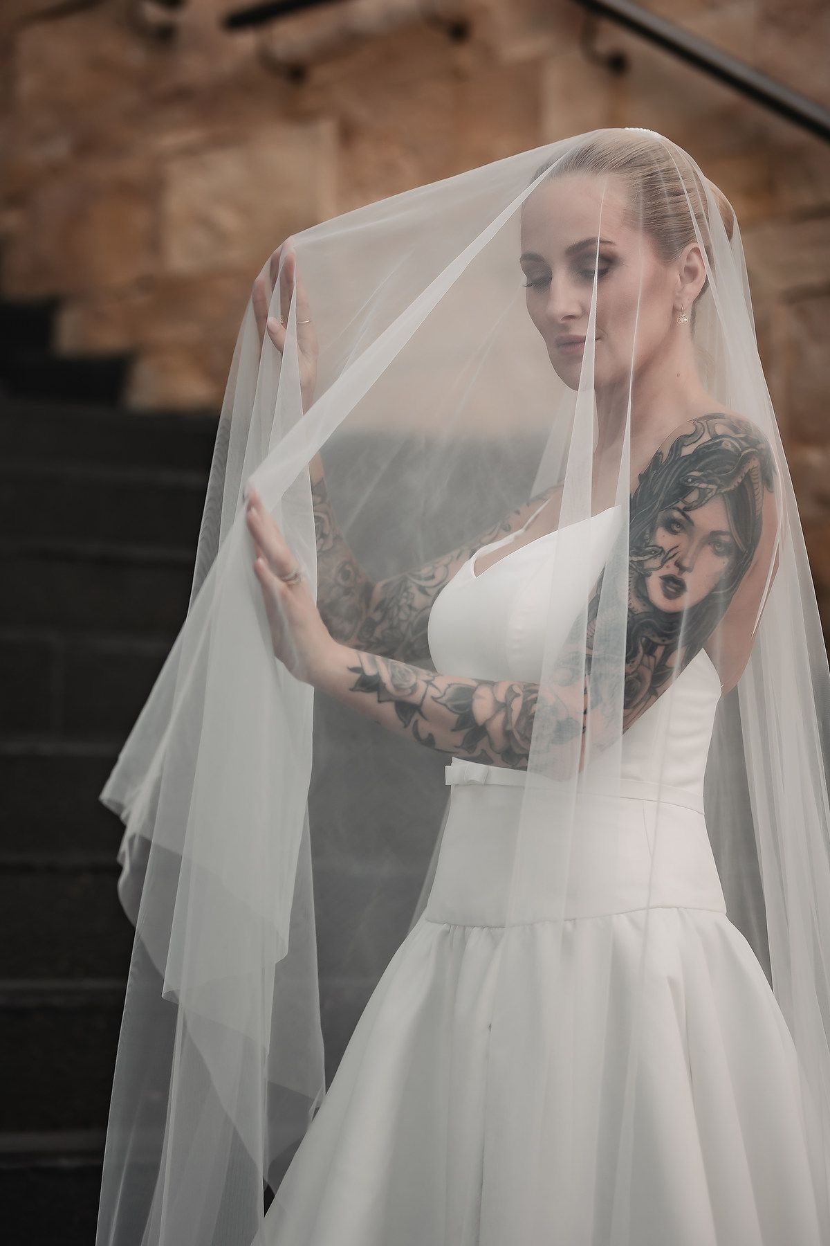 Ethereal bridal portraits with flowing veil against stone wall and steps.