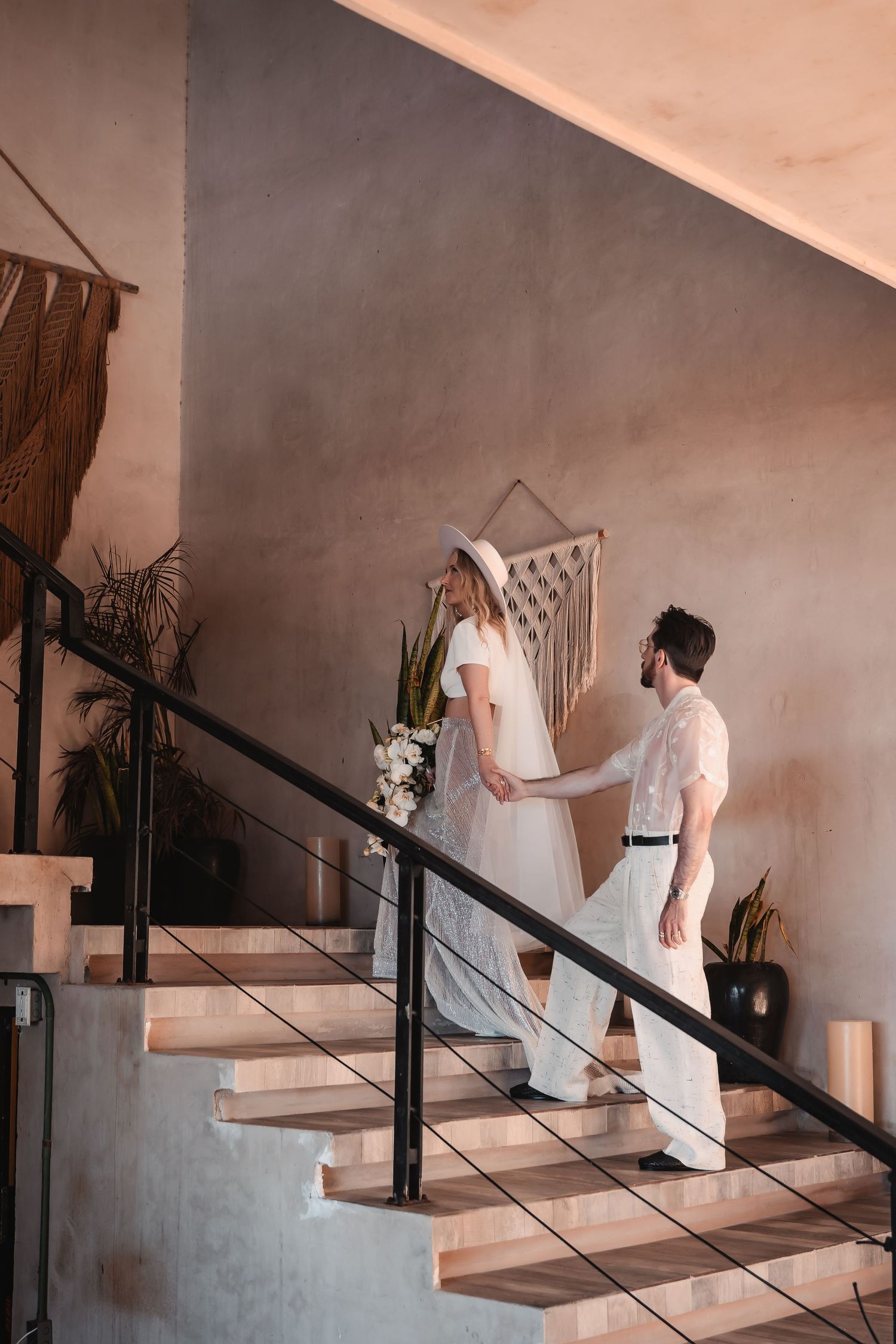 Wedding couple walking up modern concrete stairs in an industrial-style setting.