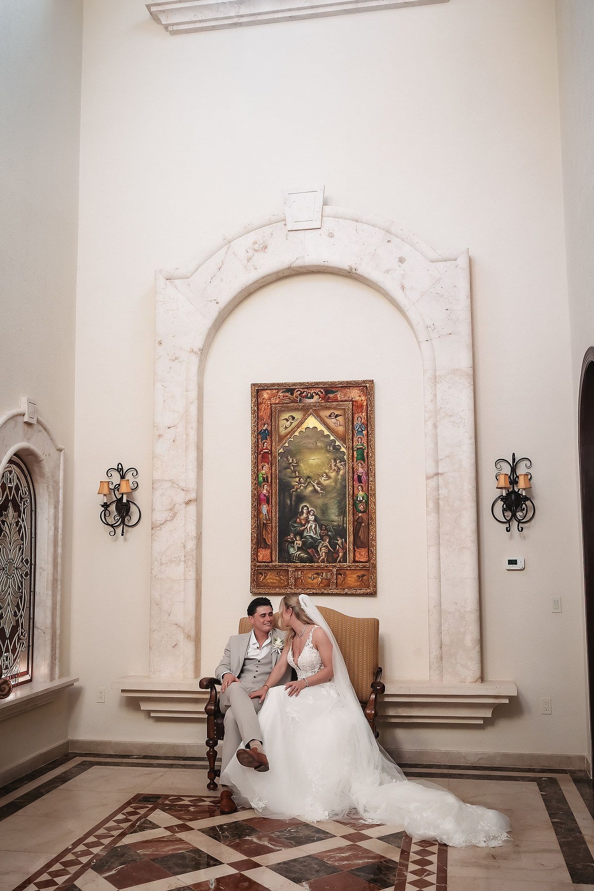 A wedding photoshoot in an elegant white hallway with arched doorways and decorative wall art.