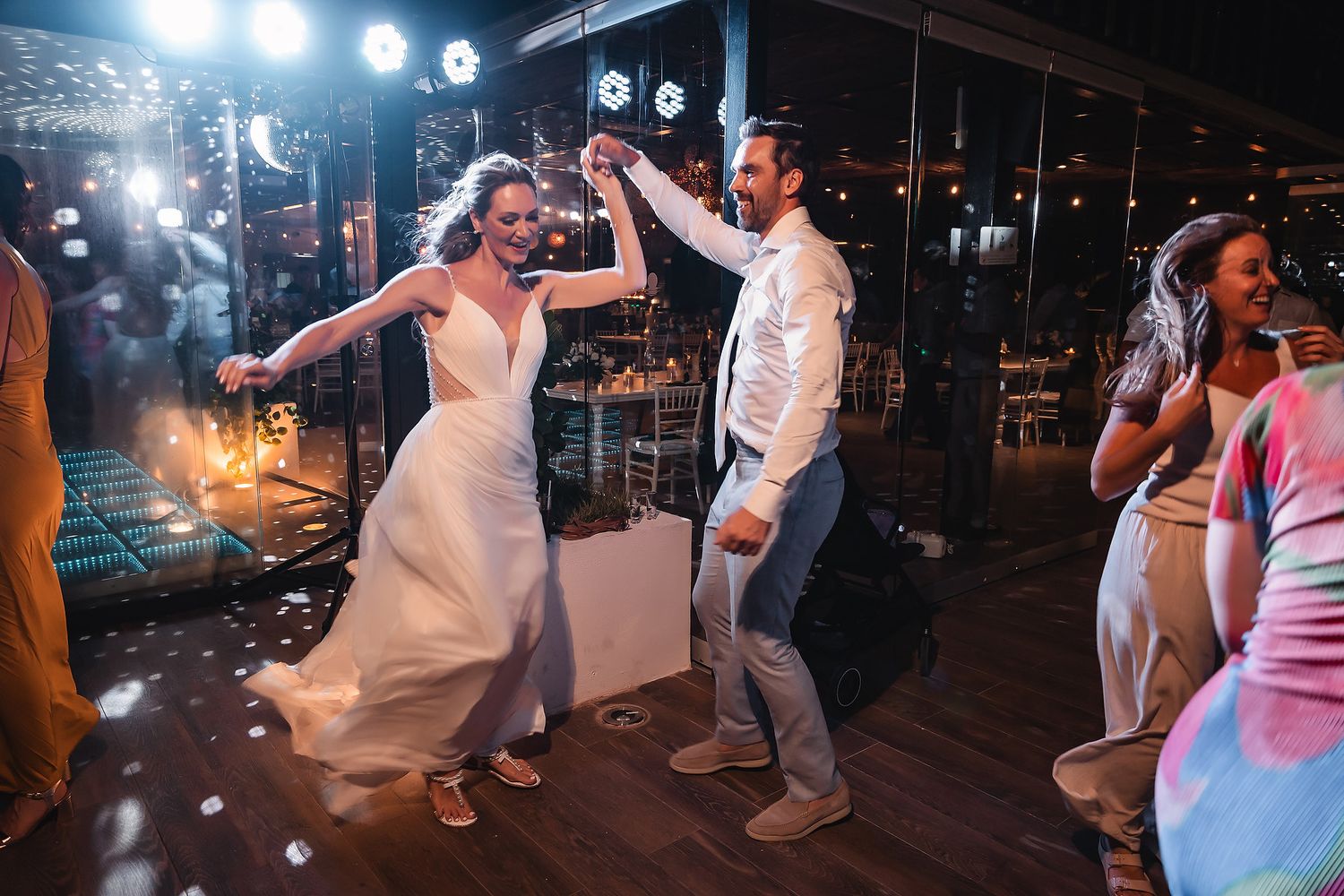 Dancers move in synchronized steps during a lively wedding reception under blue spotlights.