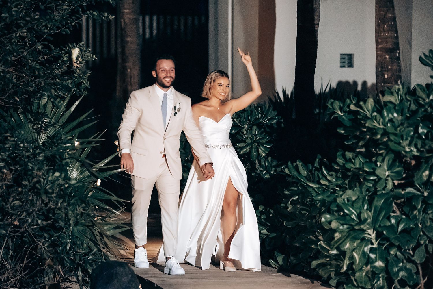 Couple in white attire dancing together at a romantic outdoor evening celebration.