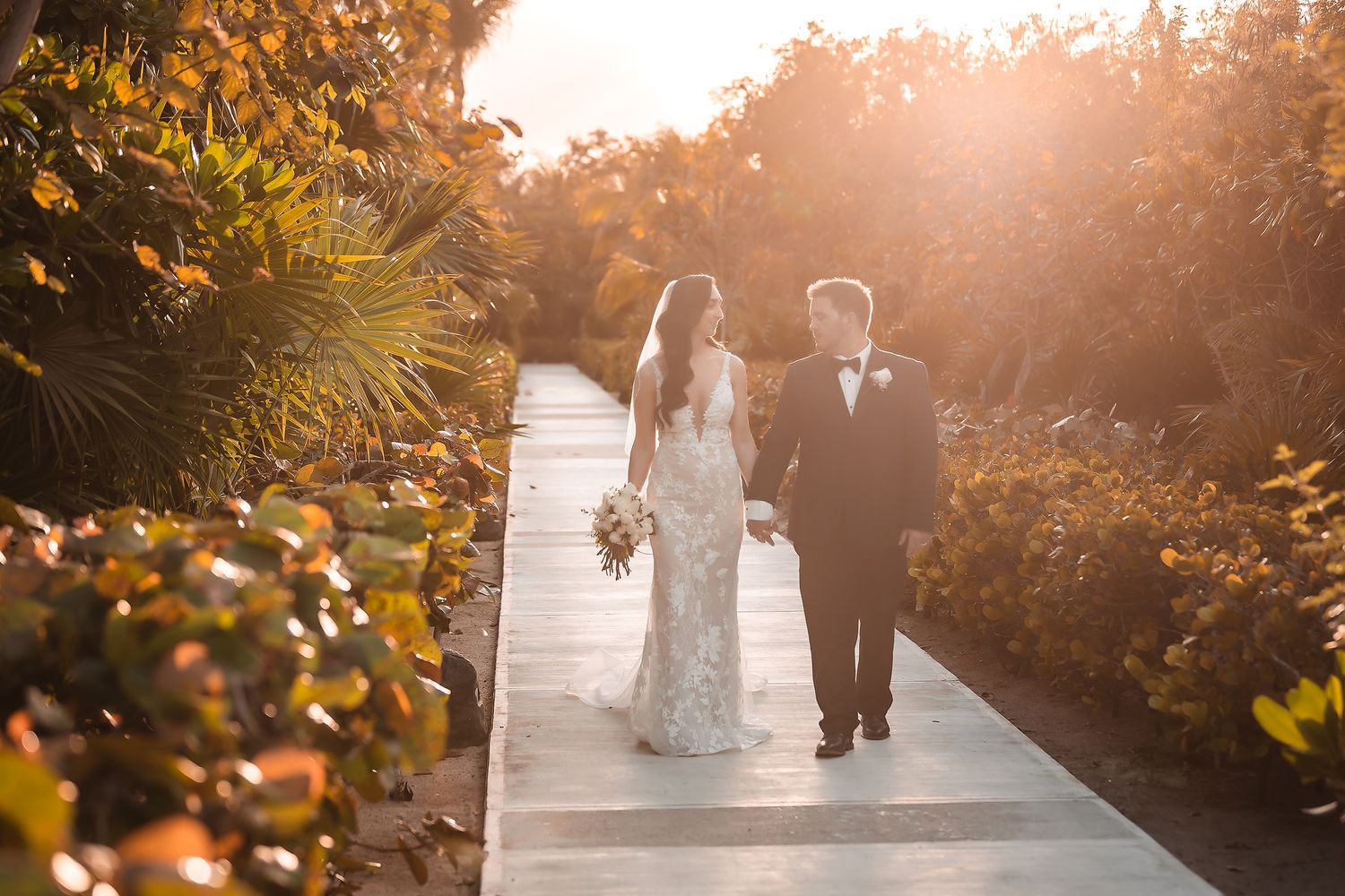 Wedding couple poses in a garden setting during golden hour sunset.