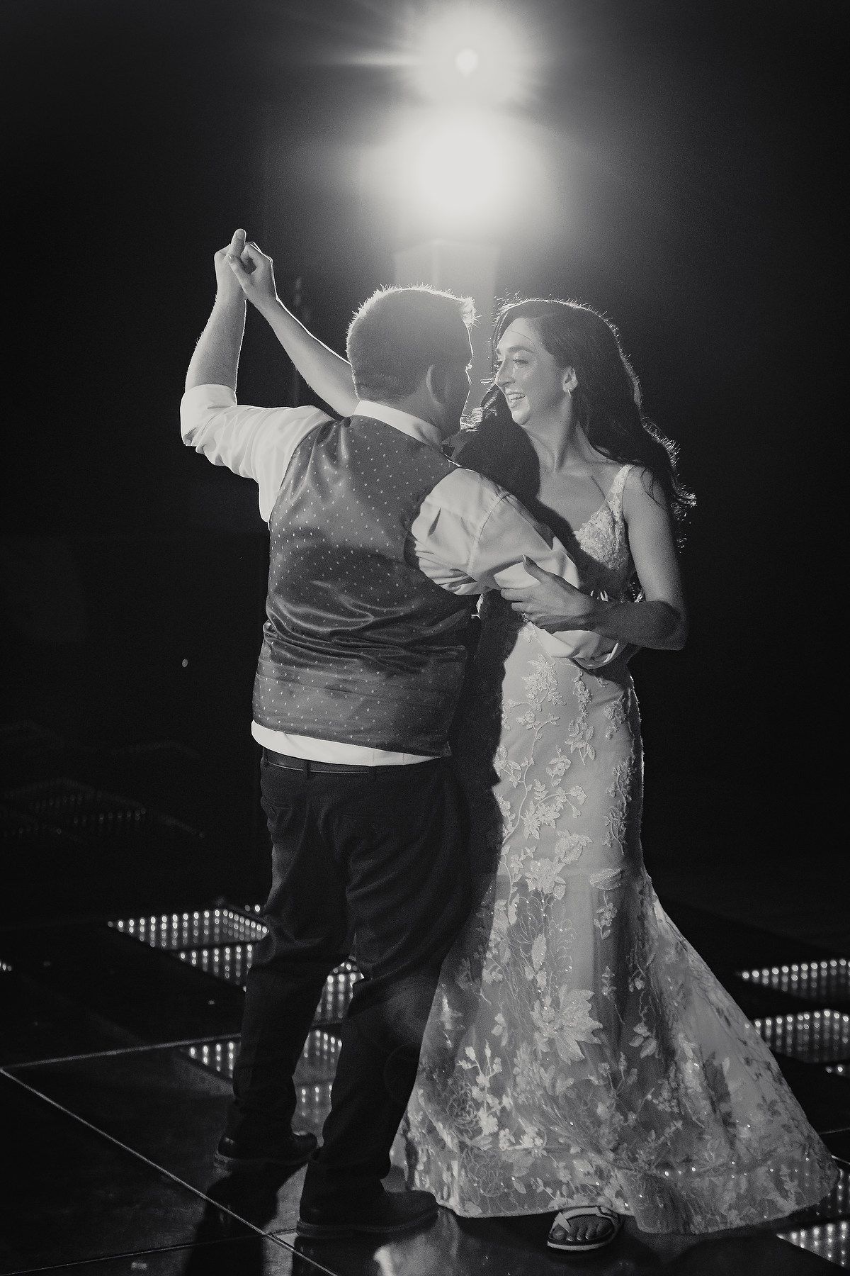 Dramatic black and white photo of a couple dancing during their first dance at a wedding reception.