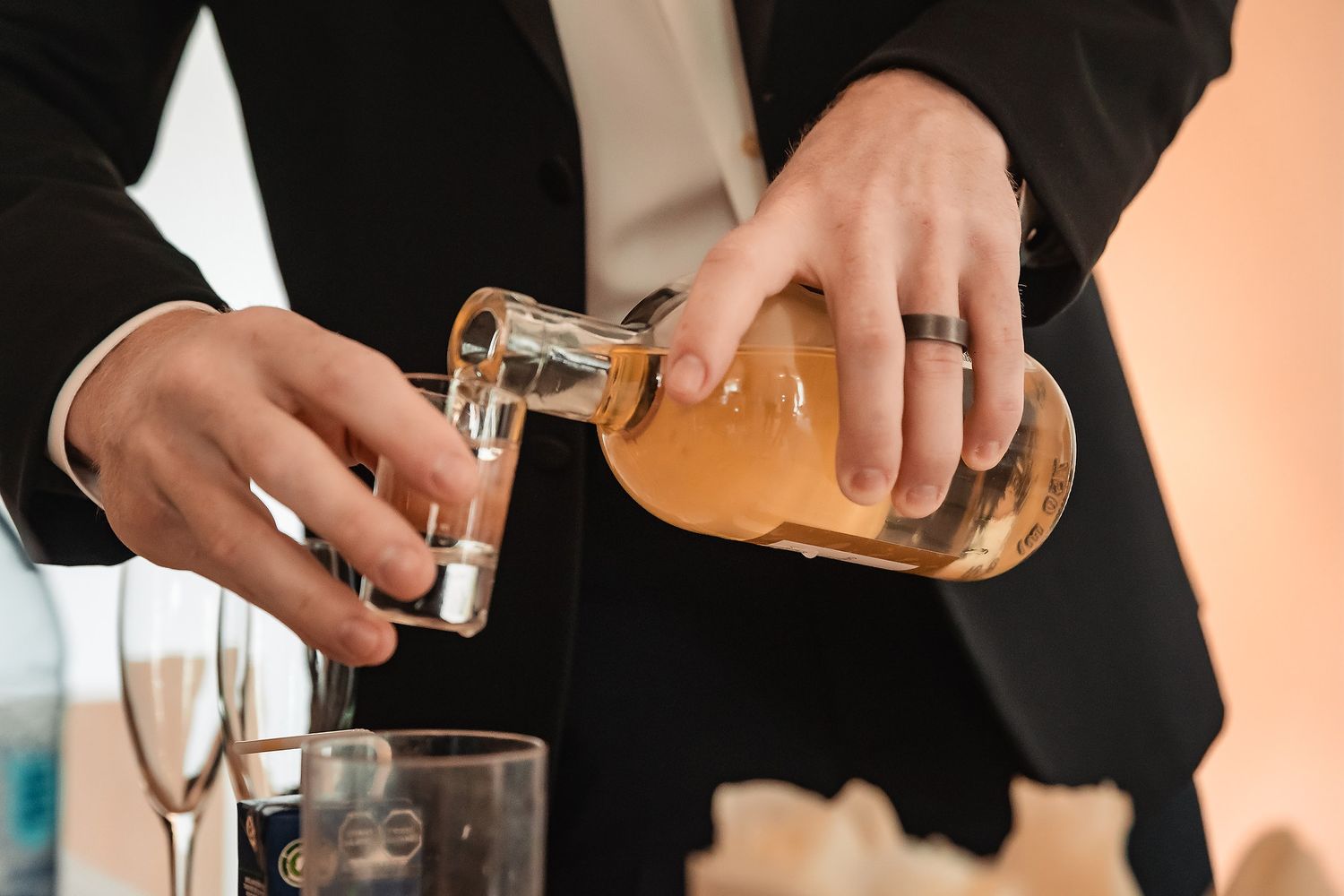 Bartender pouring an orange cocktail into a glass using professional bar equipment.