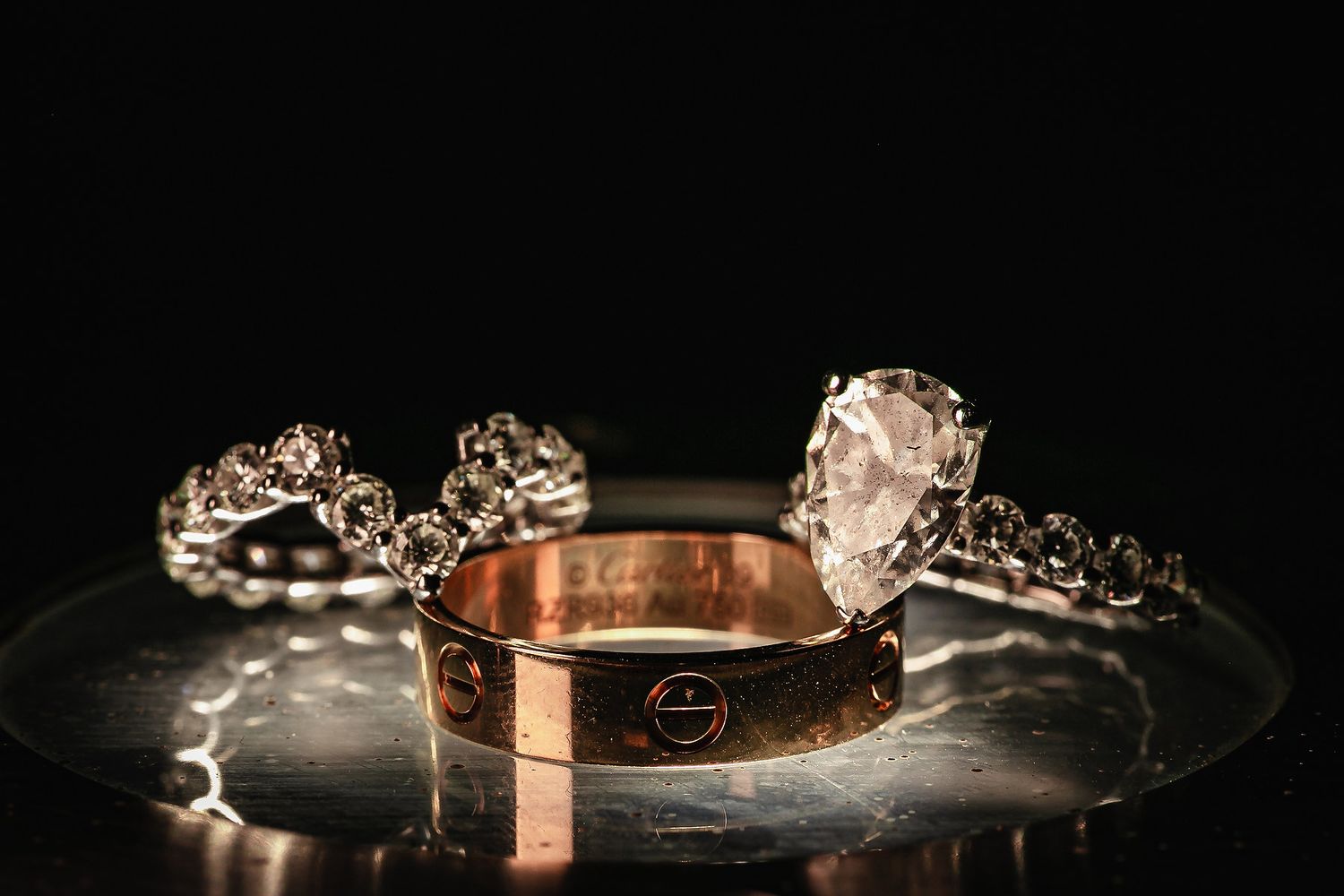 Elegant rose gold wedding bands with delicate crystal details sparkle against a dark background.