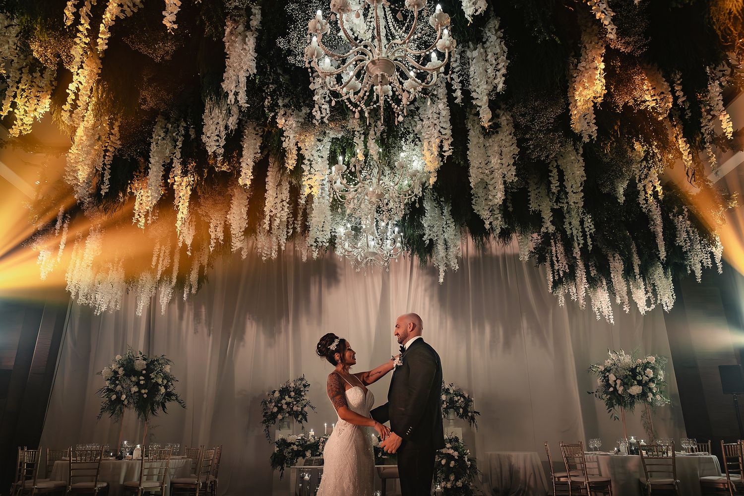 A couple shares their first dance under a dramatic canopy of hanging crystal decor at an elegant wedding reception.