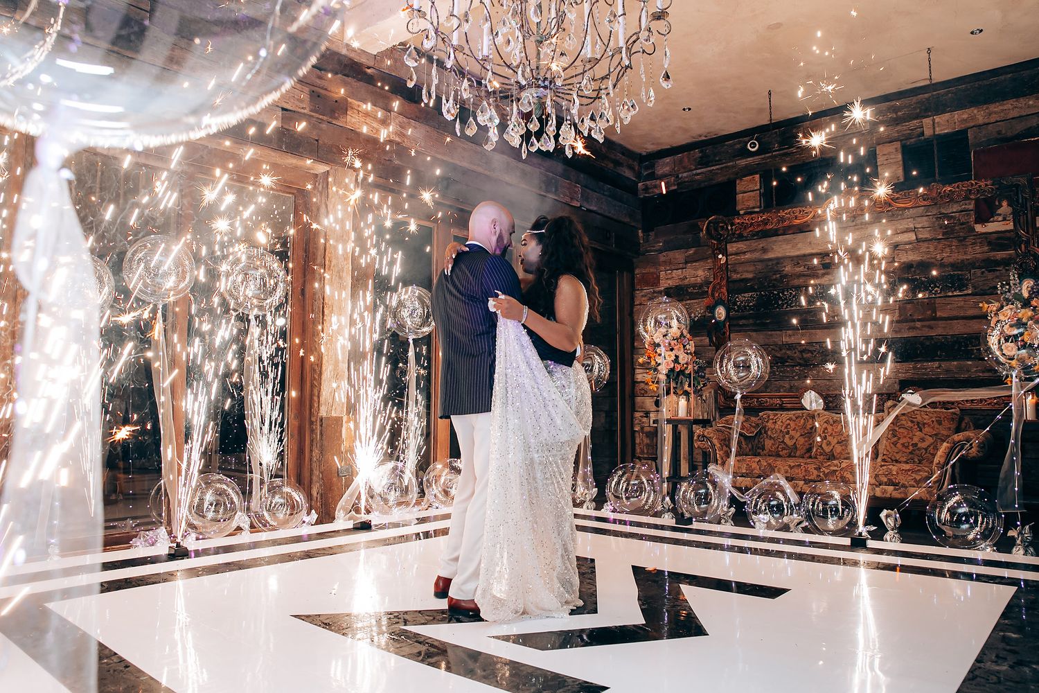 Wedding couple shares their first dance surrounded by sparkler fountains in an elegantly decorated ballroom.