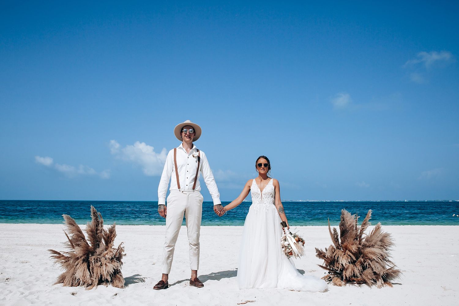 Panoramic beach wedding scene with white sand, blue ocean, and tropical decor.