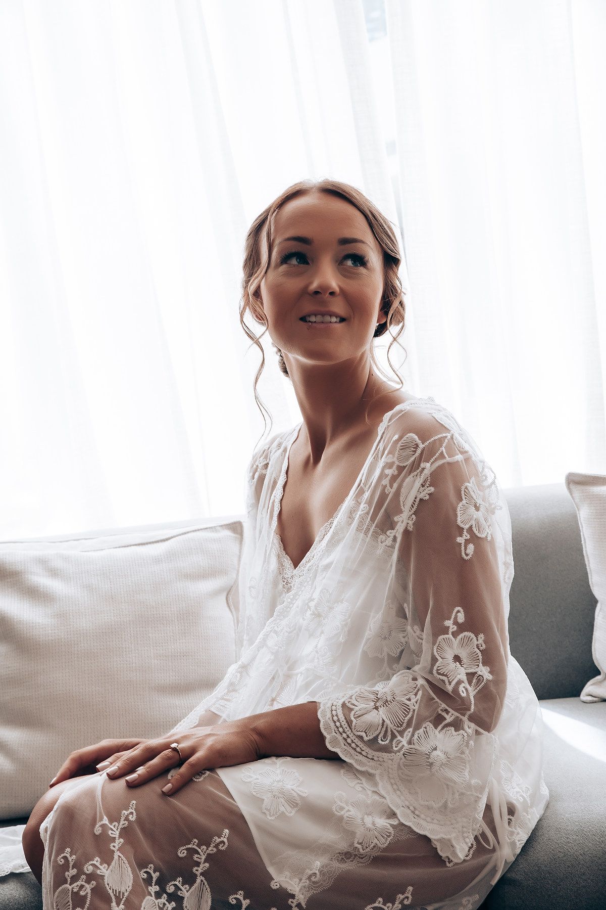 Elegant white lace bridal robe with sheer details in natural window light.