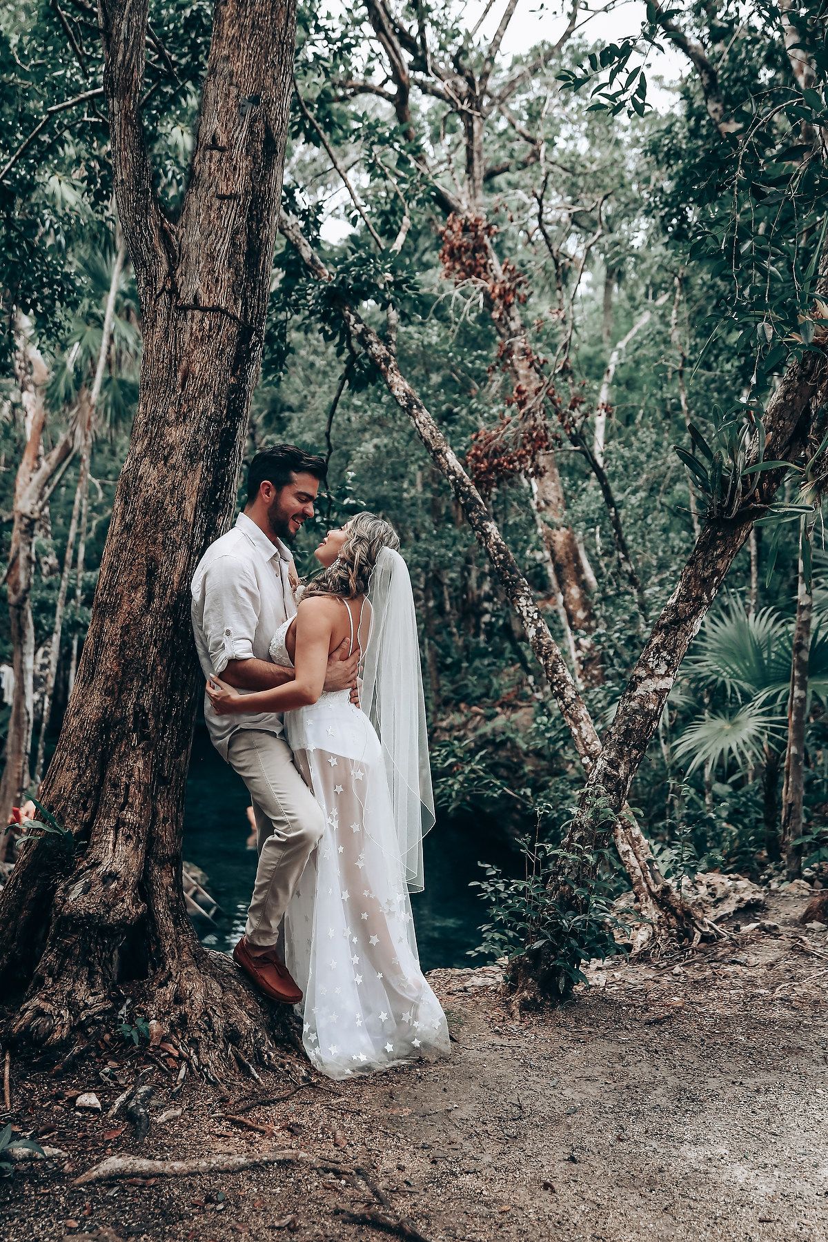 A romantic wedding moment captured in a lush forest setting with natural light filtering through trees.