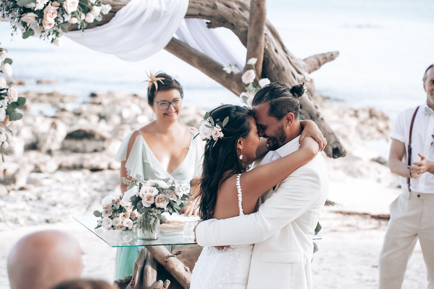 Beachside wedding celebration with white floral arrangements and natural coastal scenery.