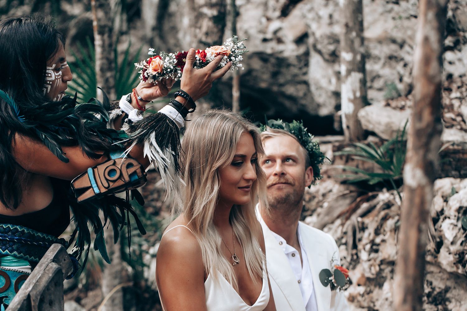 A romantic outdoor ceremony takes place in a forest setting with white and natural decorations.