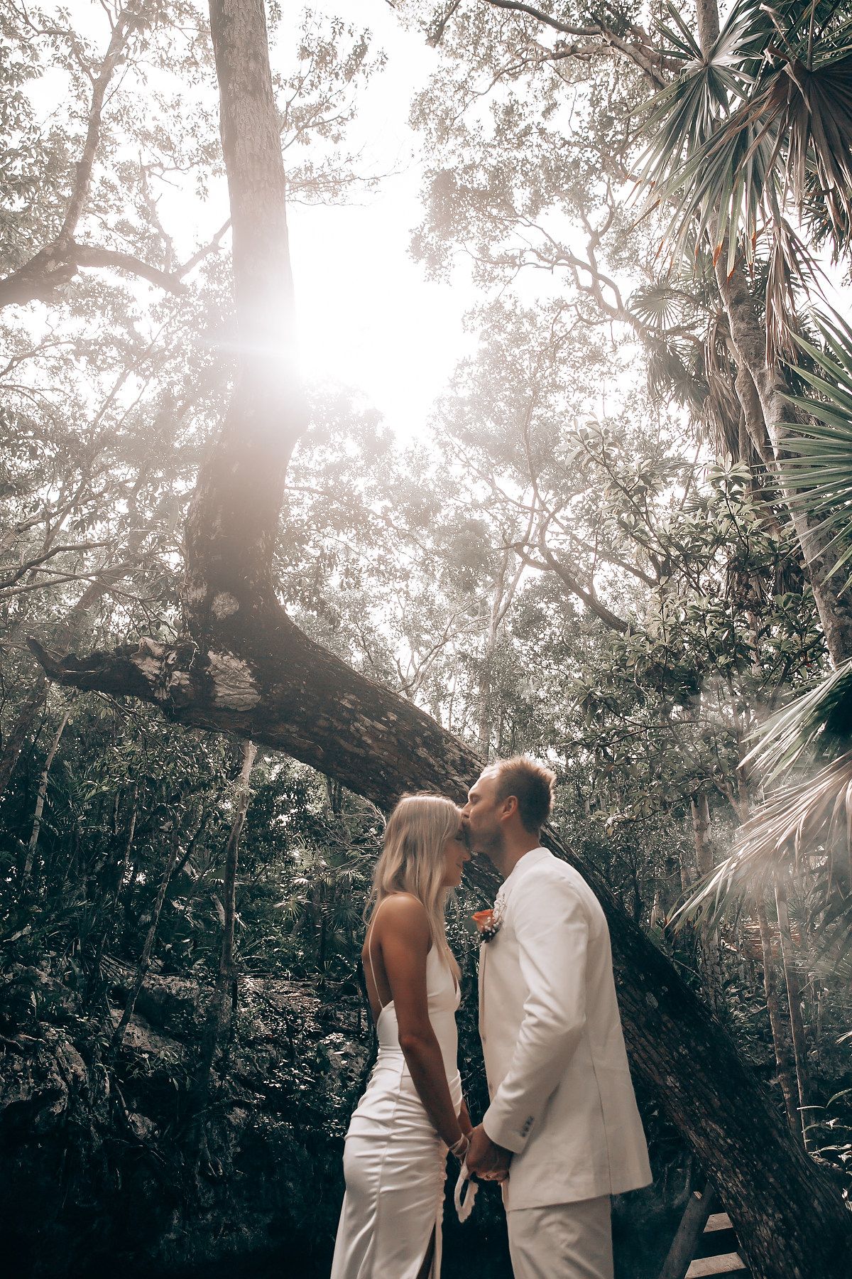 Sunlit forest wedding scene with palm trees and natural lighting creating a romantic atmosphere.