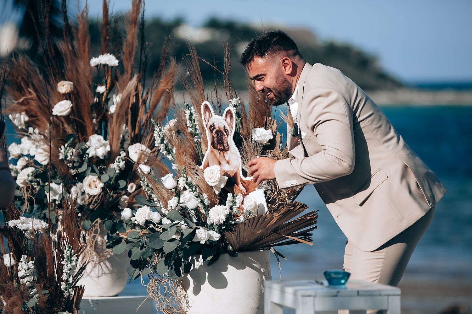 Romantic beach wedding ceremony setup with white floral arrangements and ocean backdrop.