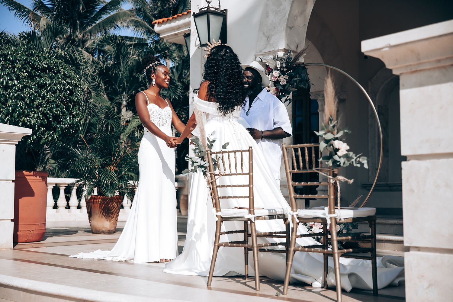Outdoor wedding venue with white columns and tropical garden setting.